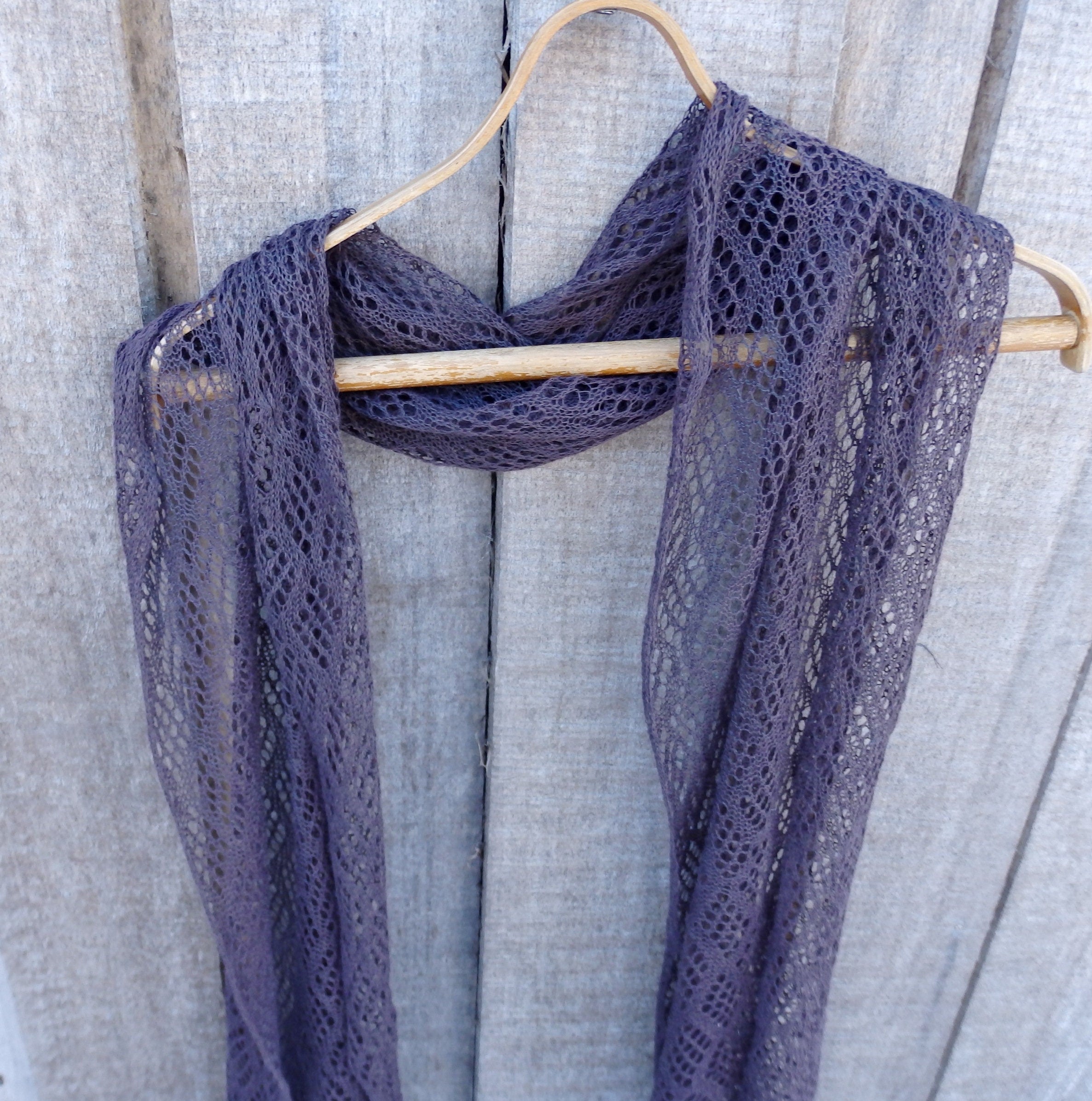 Purple lace scarf on a wooden hanger against a wooden background