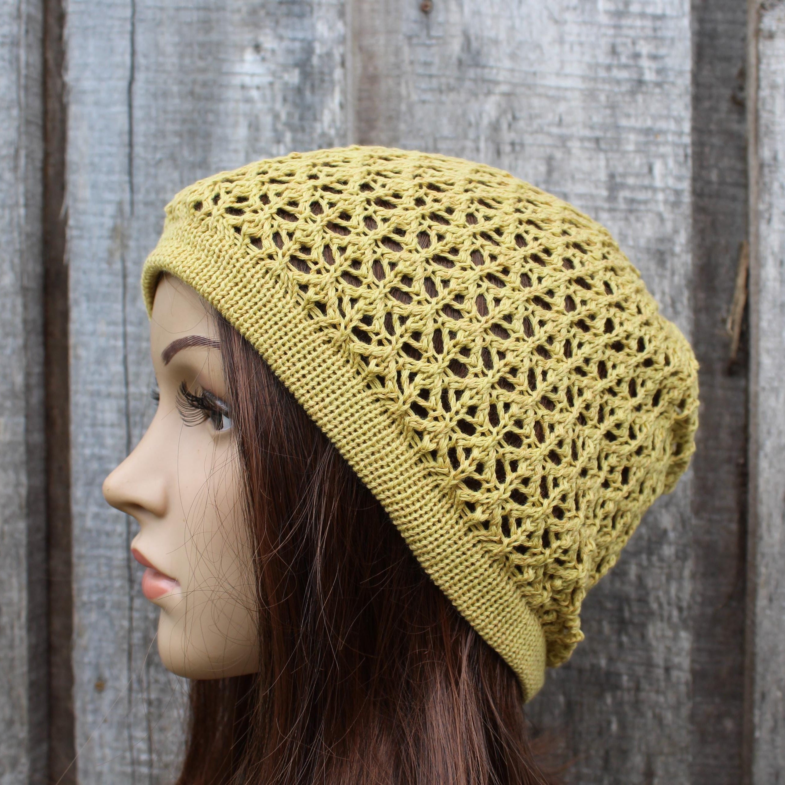 Yellow knitted beanie worn by a mannequin against a wooden background