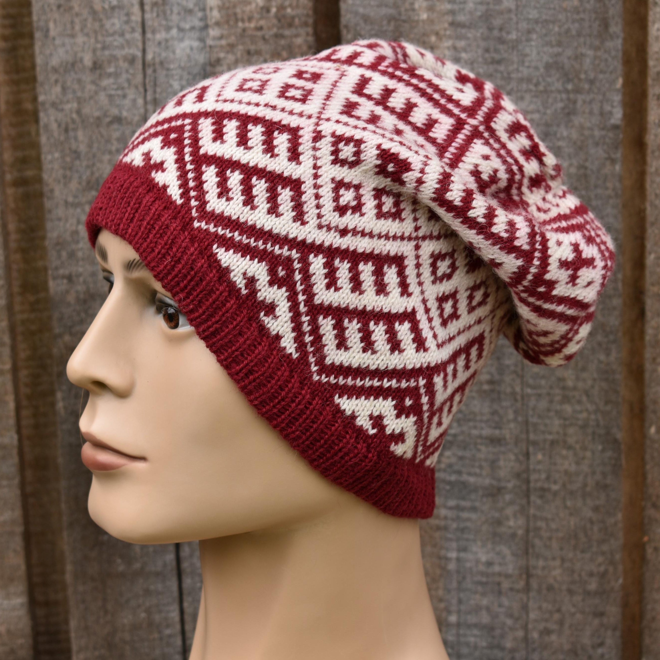 Red and white patterned knitted beanie on a mannequin head against a wooden background