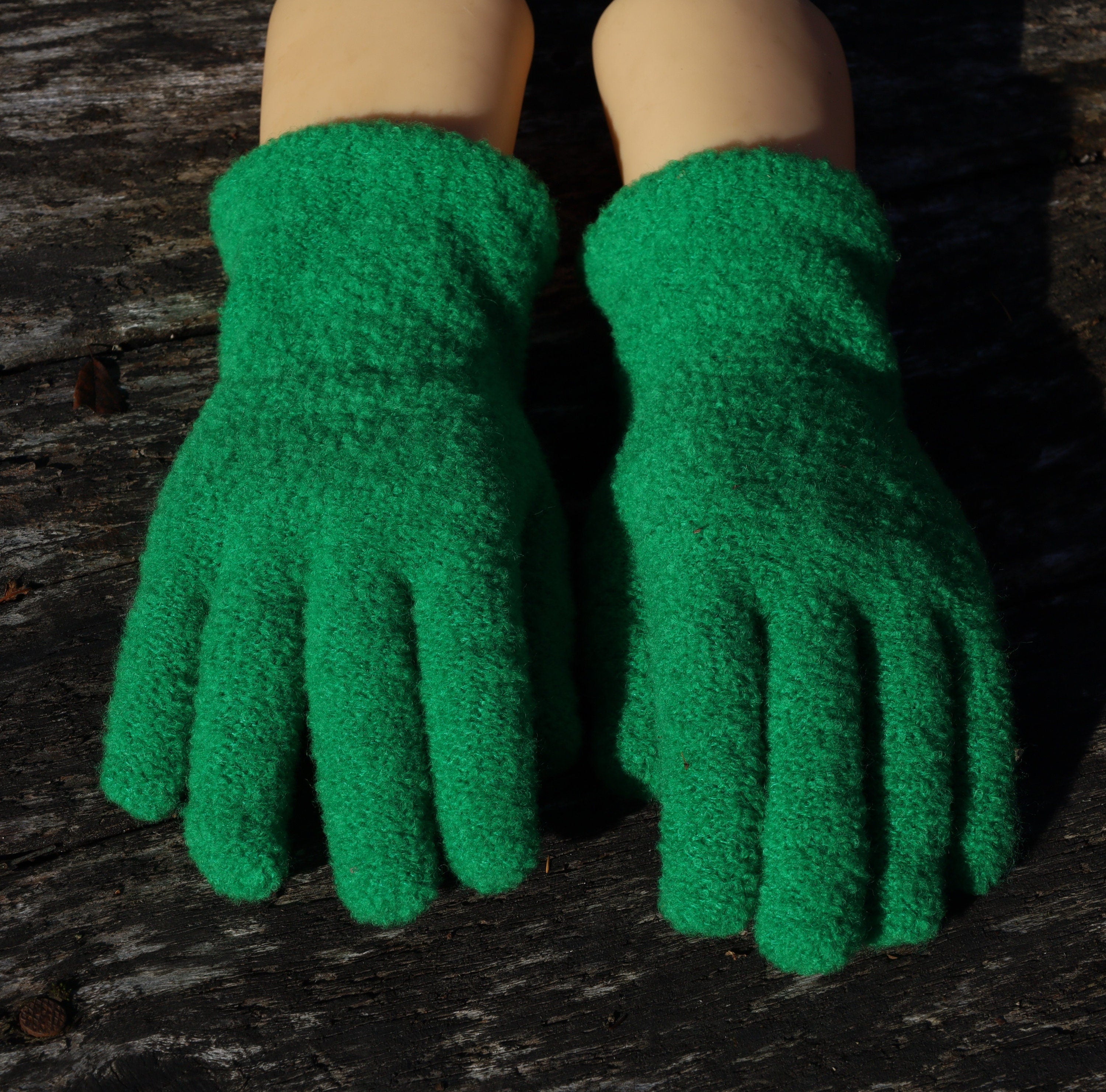 Green fingerless gloves on a wooden surface