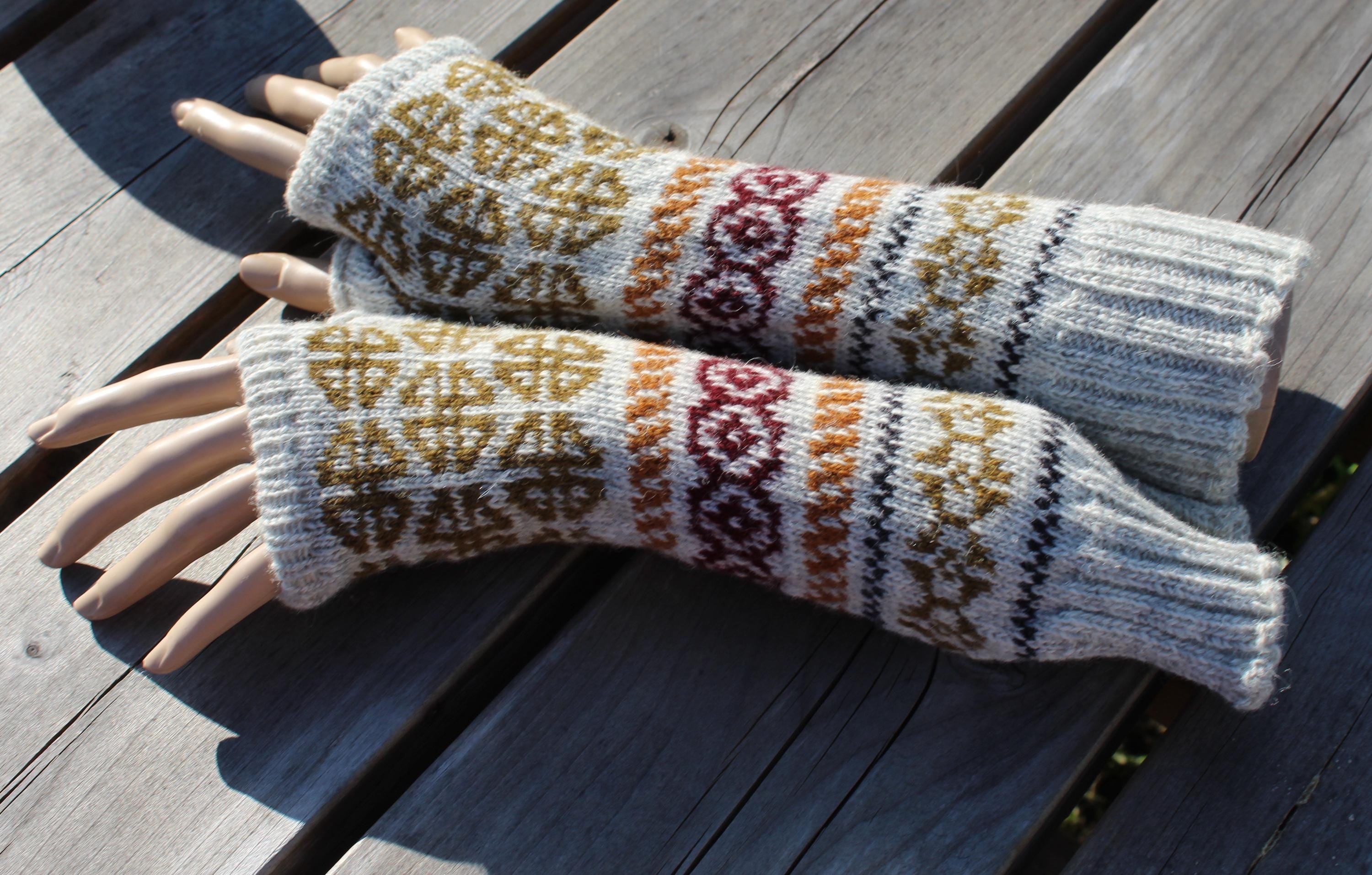 Pair of knitted fingerless gloves with a pattern on a wooden surface
