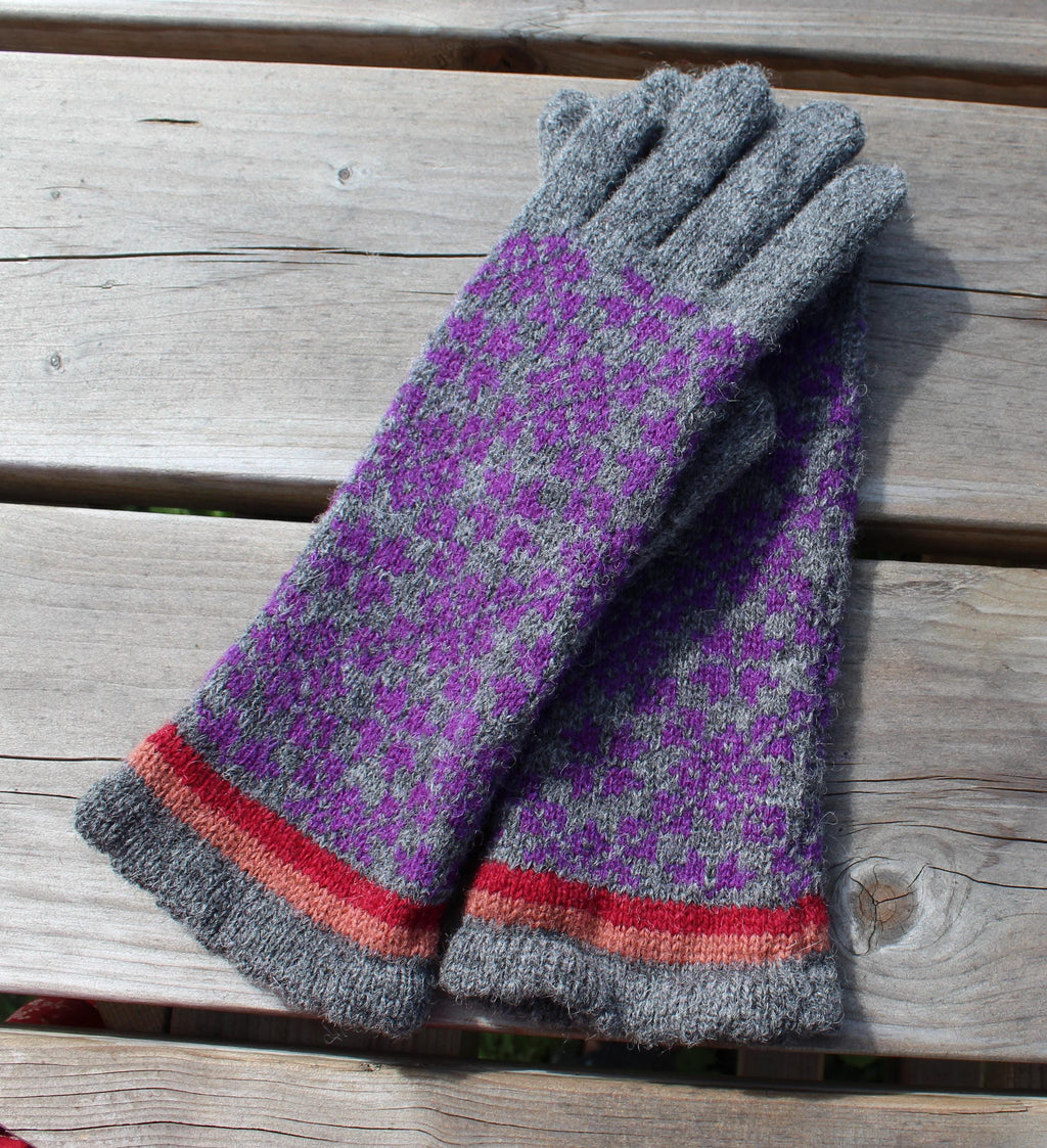 Pair of gray and purple gloves with red accents on a wooden surface
