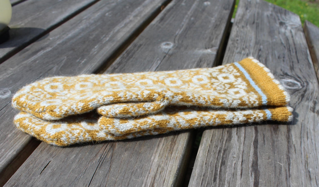 Pair of yellow and white patterned oven mitts on a wooden surface