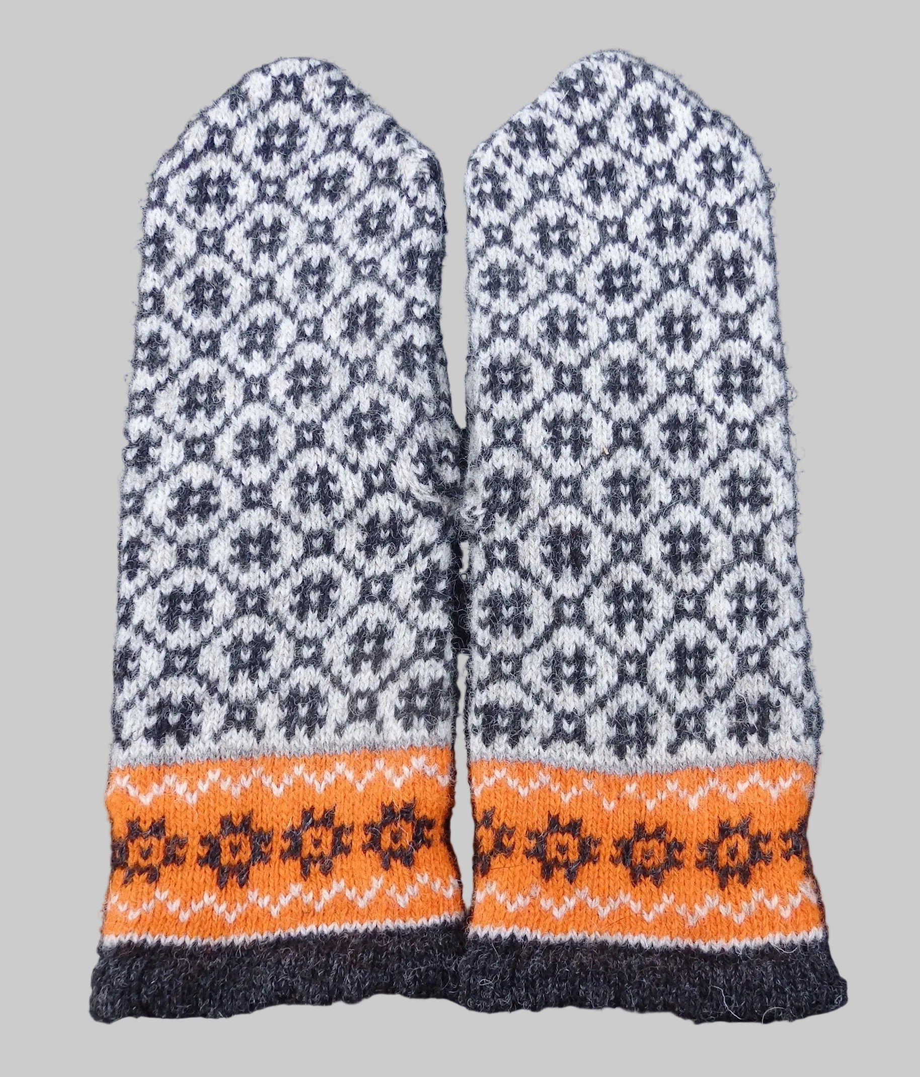Pair of knitted mittens with a geometric pattern on a dark background