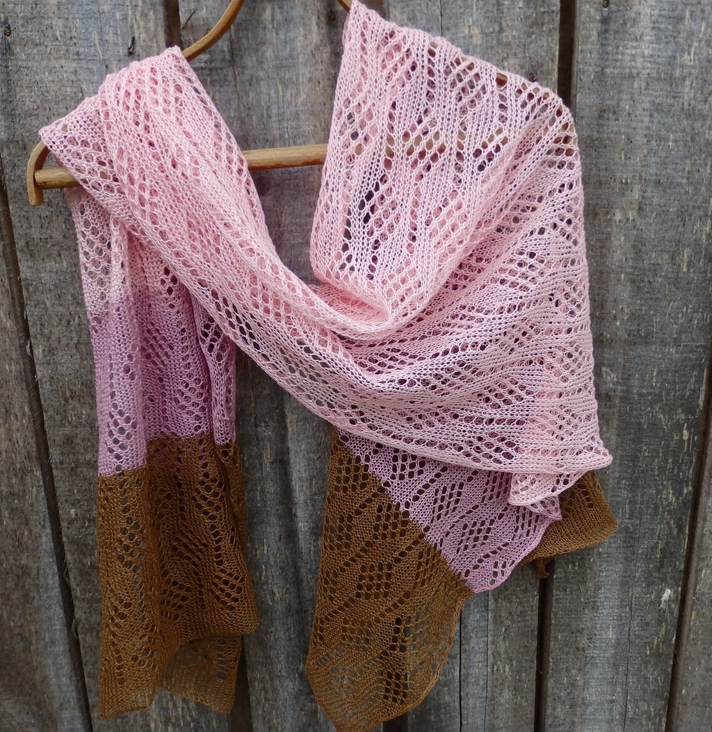 Pink and brown knitted shawl hanging on a wooden surface
