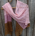 Pink and brown knitted shawl hanging on a wooden surface