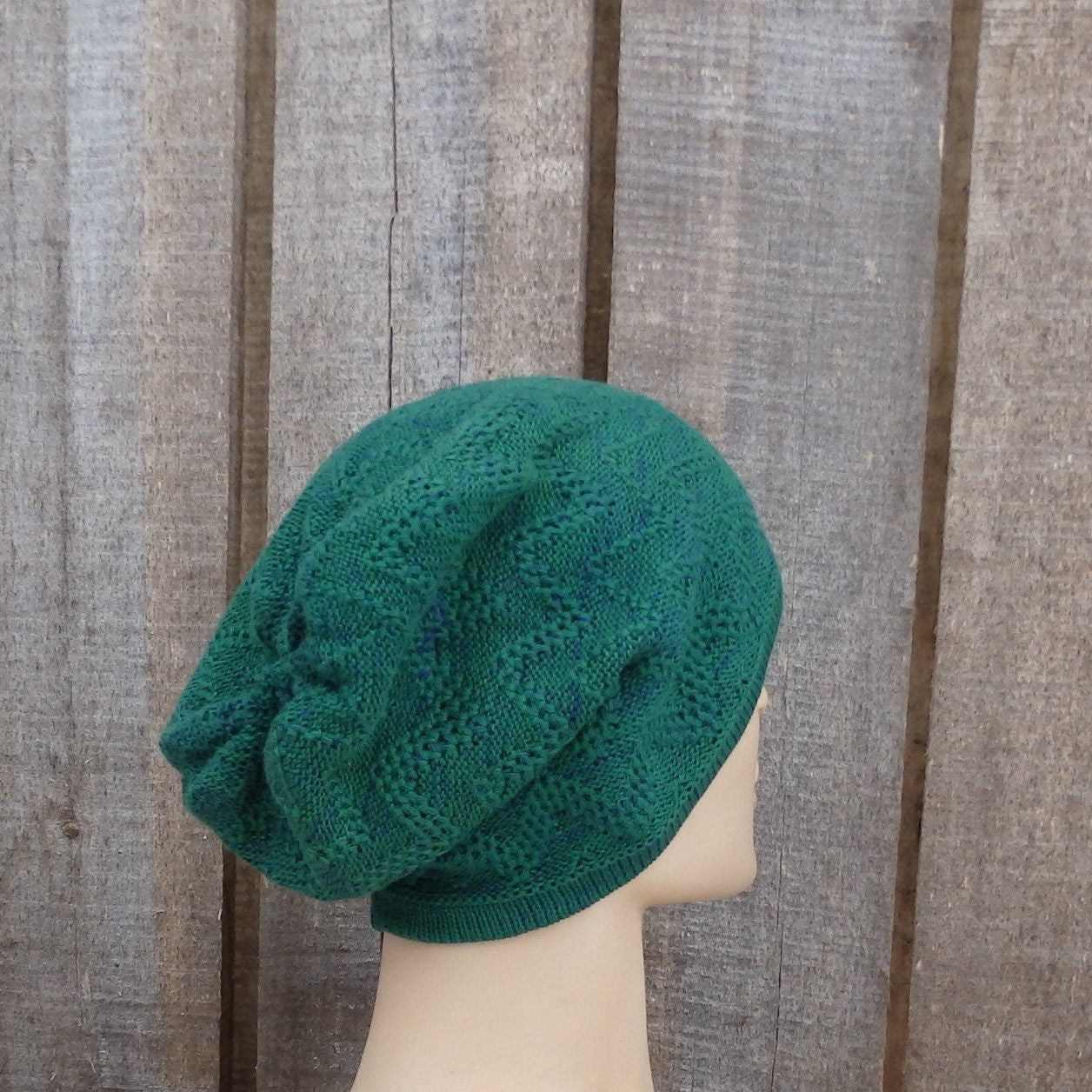 Green knitted beanie on a mannequin head against a wooden background