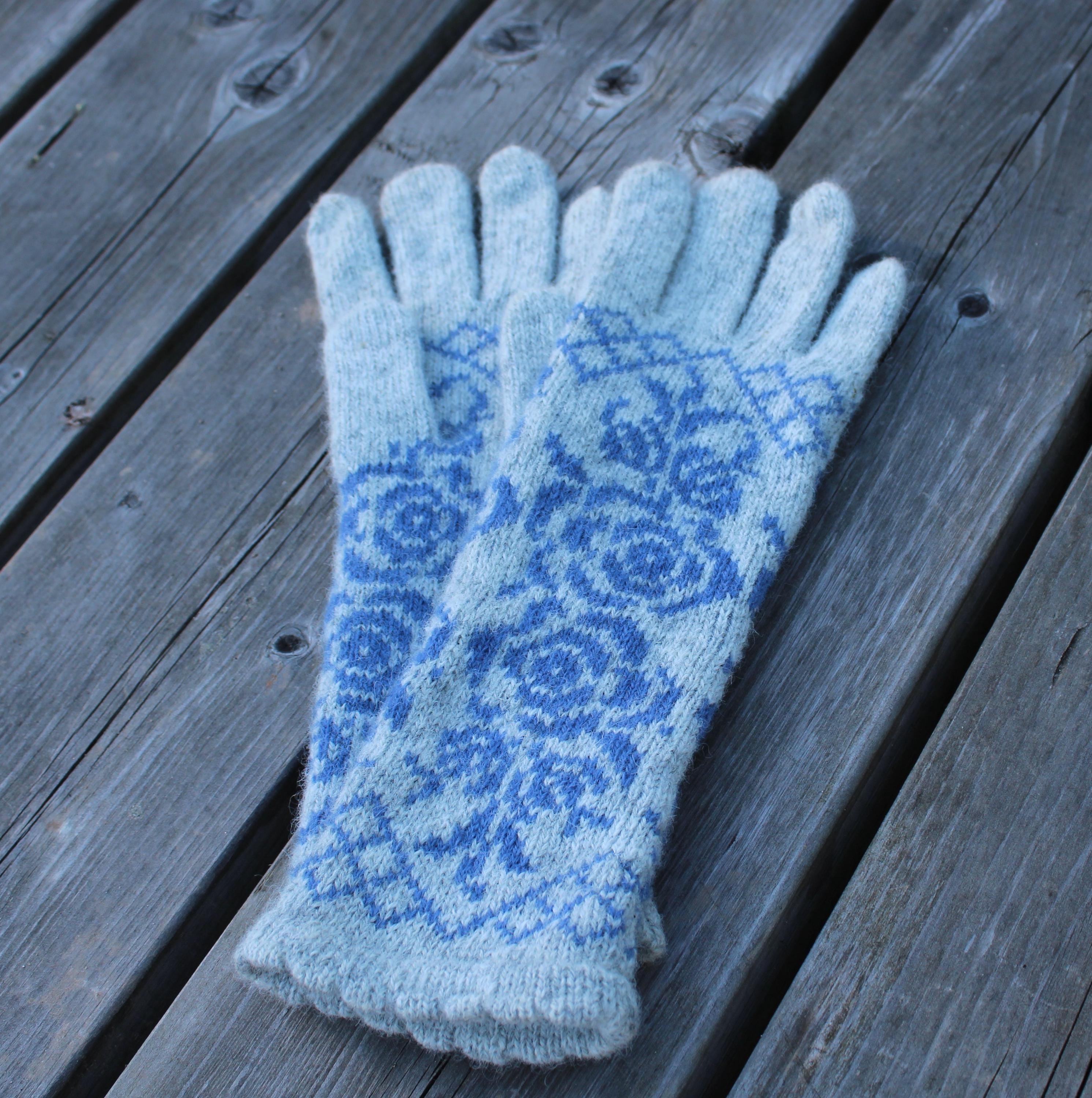 Pair of blue patterned gloves on a wooden surface