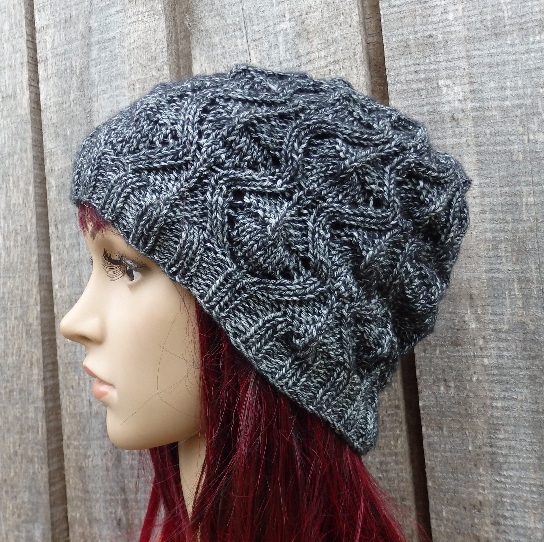 Knitted gray beanie on a mannequin head with red hair against a wooden background