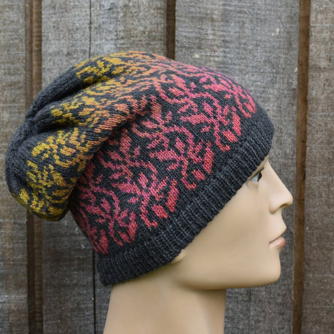 Knitted hat with a pattern on a mannequin head against a wooden background