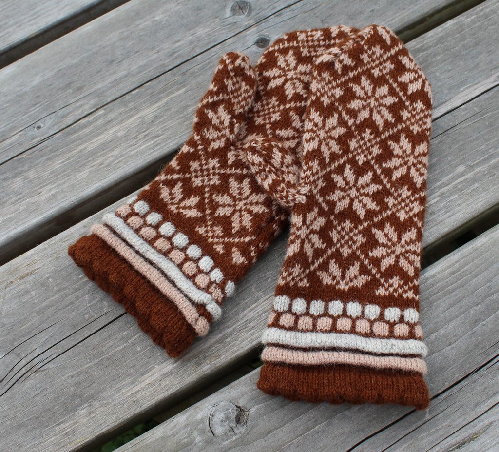 Pair of brown and white patterned mittens on a wooden surface
