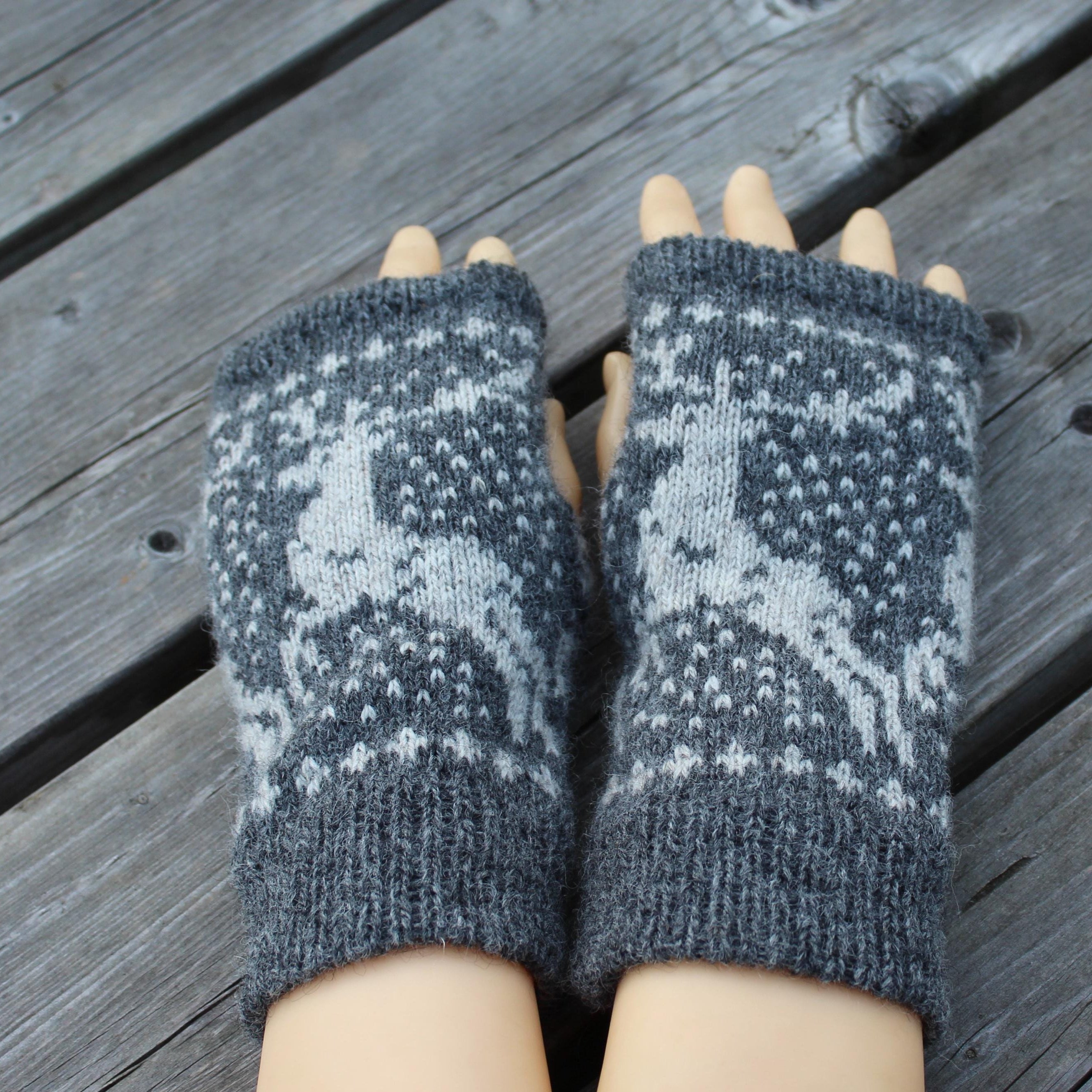 Pair of gray and white patterned fingerless gloves on a wooden surface