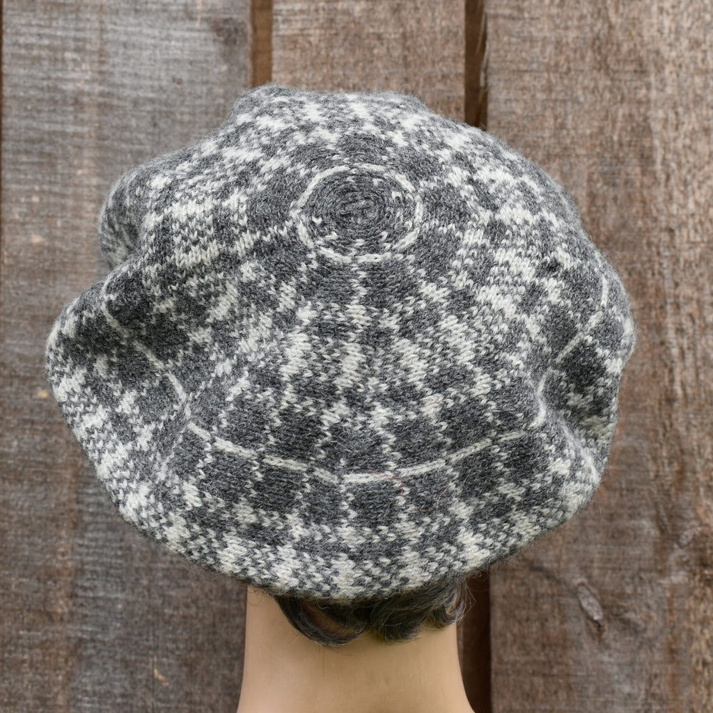 Textured gray and white knit beret against a wooden background