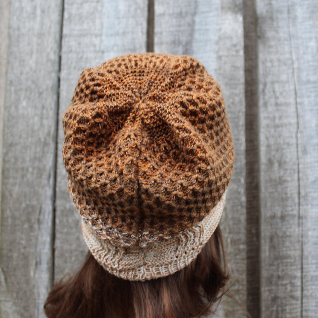 Knitted beanie with gradient color pattern against a wooden background