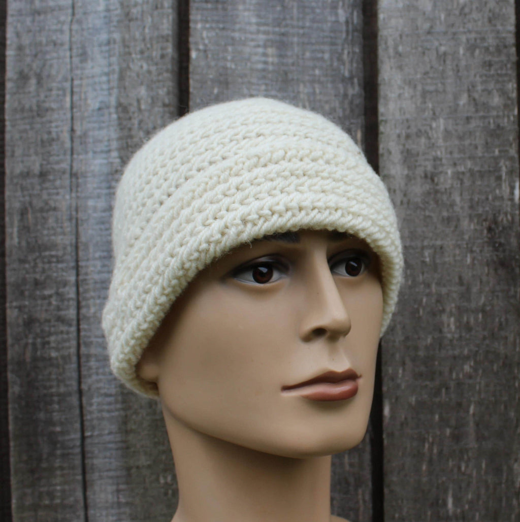 Mannequin head wearing a cream knitted beanie against a wooden background