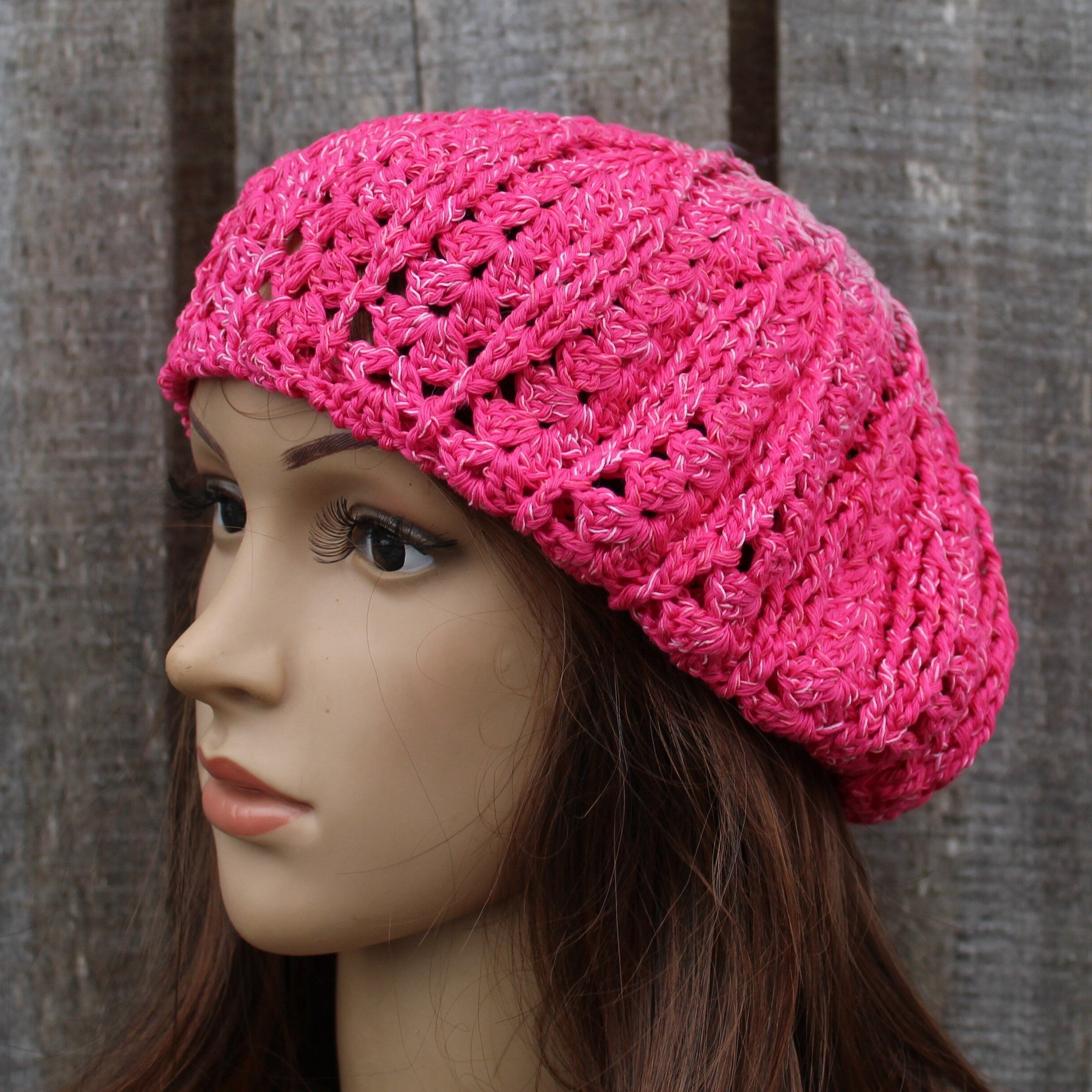 Pink crocheted beret on a mannequin head against a wooden background