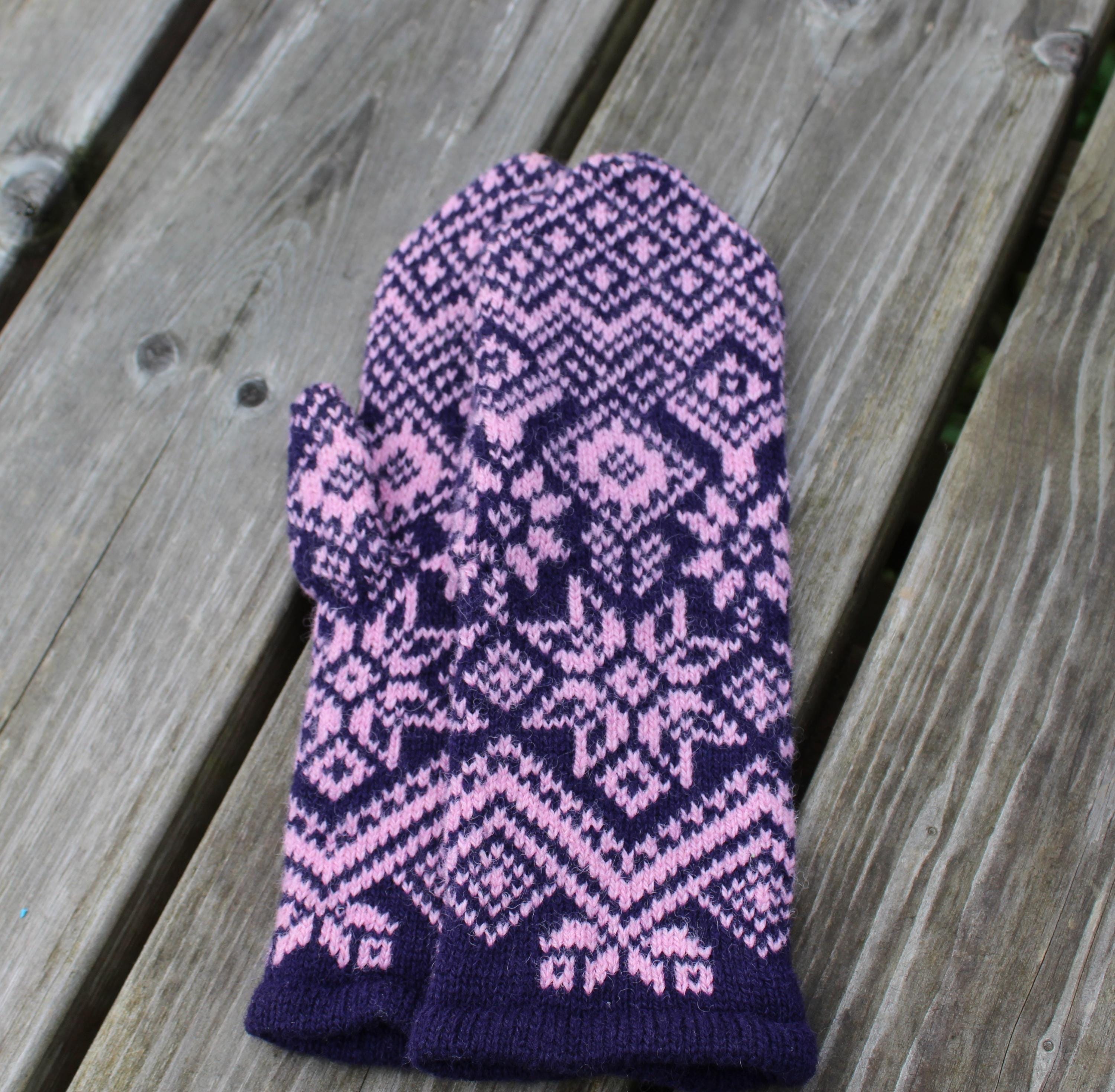 Purple and pink patterned knitted mitten on a wooden surface