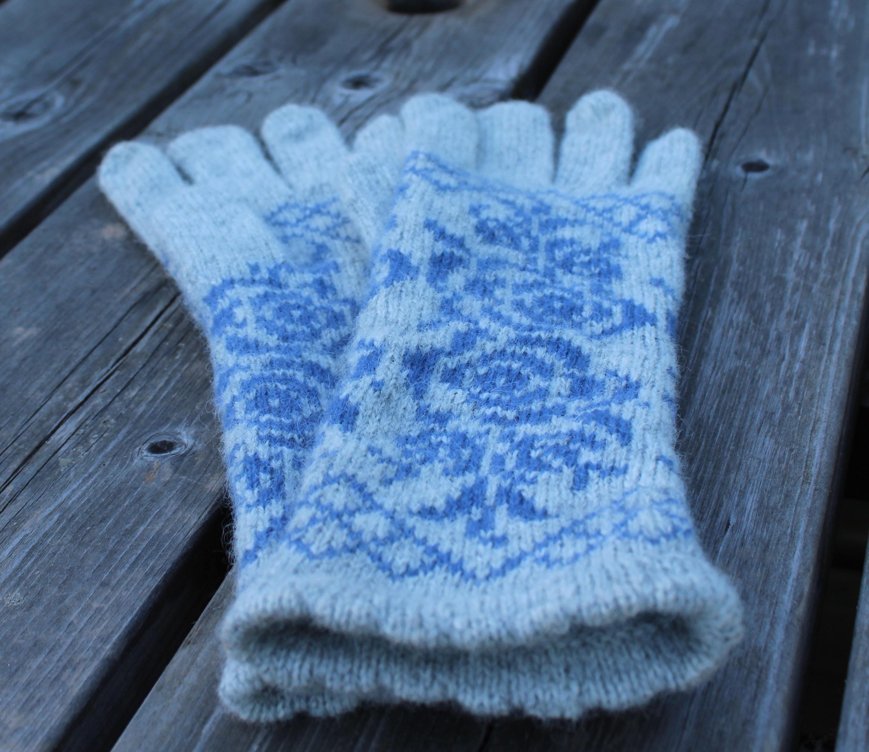 Pair of light blue knitted gloves with a subtle pattern on a wooden surface