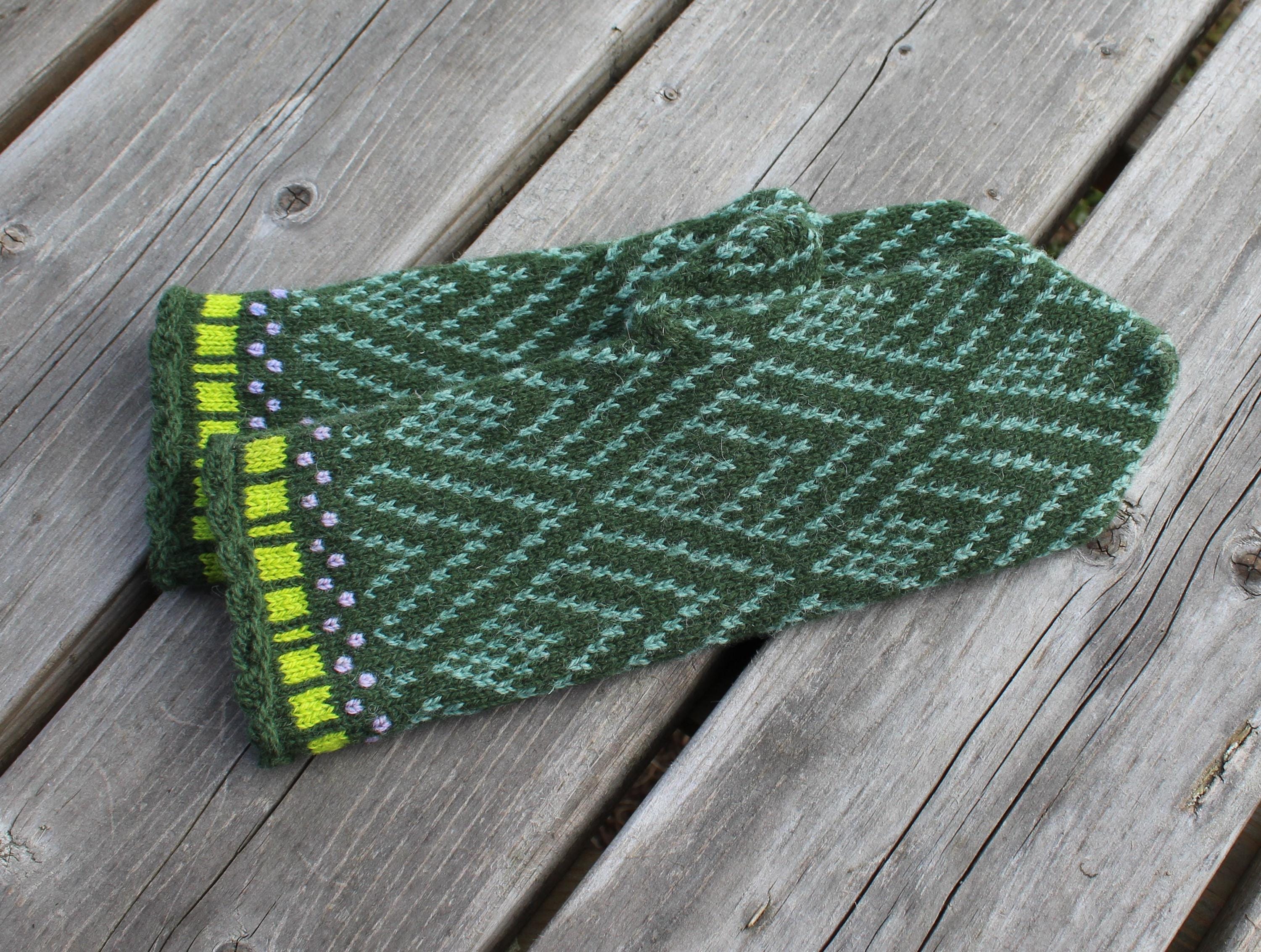 Green knitted glove with a pattern on a wooden surface