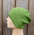 Green knitted beanie on a mannequin head against a wooden background