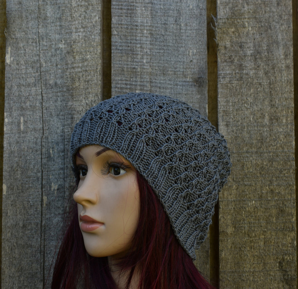 Mannequin head wearing a gray knit hat against a wooden background