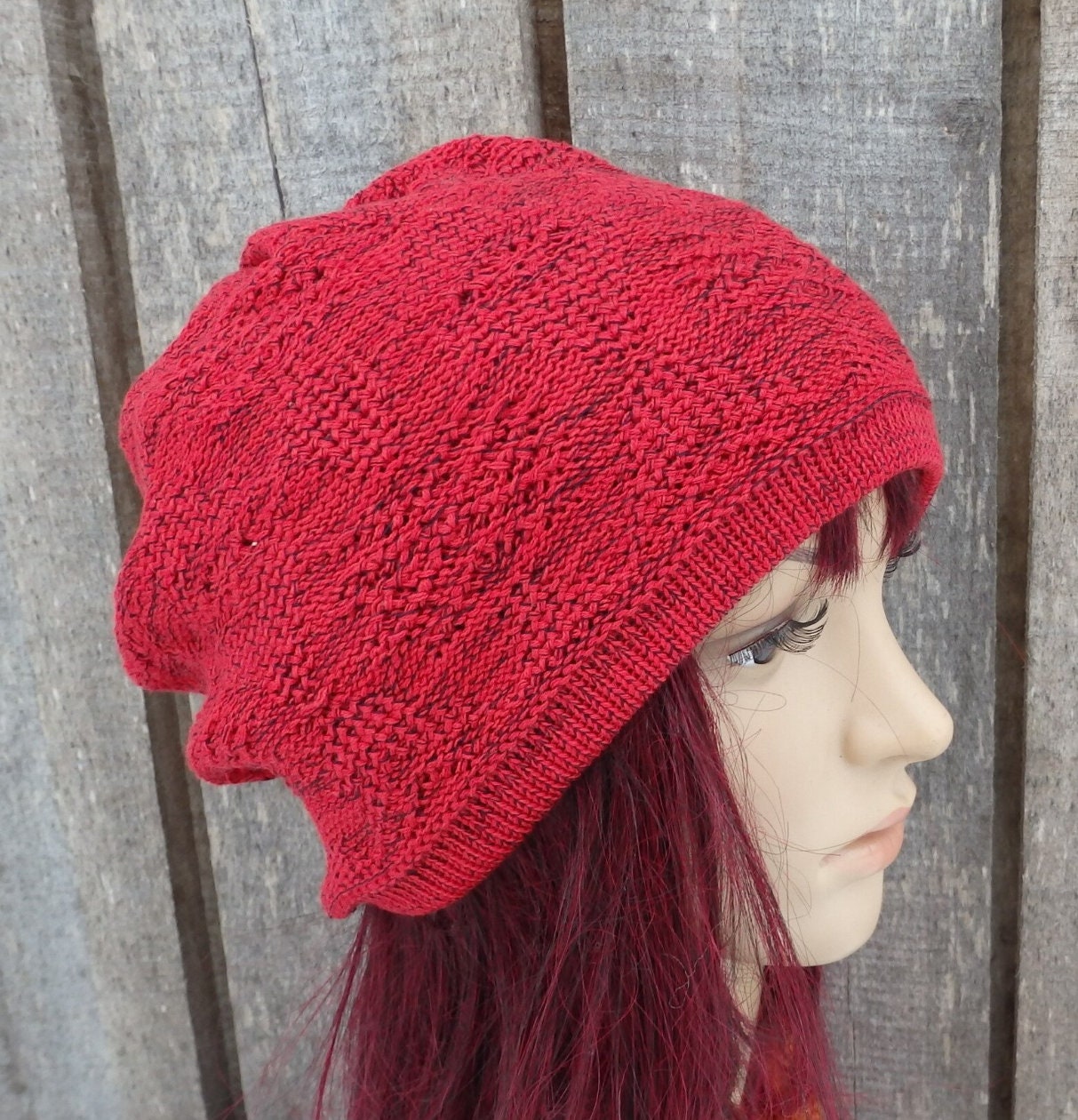 Red knitted beanie on a mannequin head against a wooden background