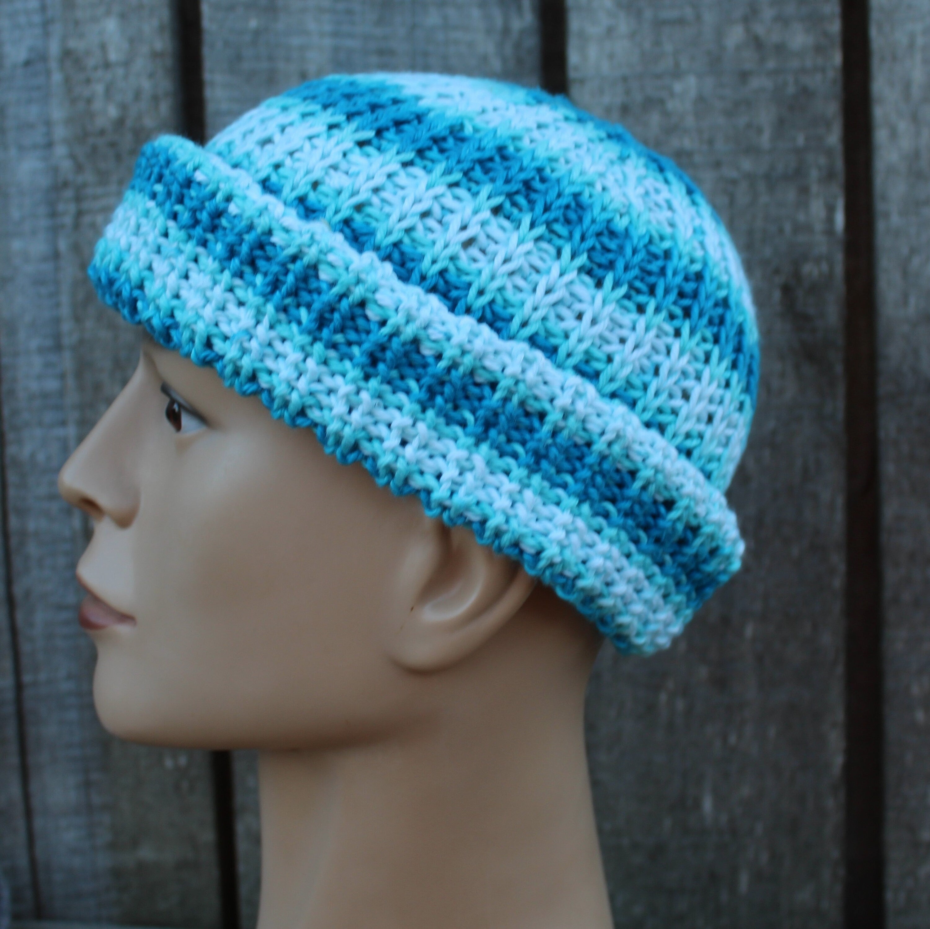 Blue knitted beanie on a mannequin head against a wooden background