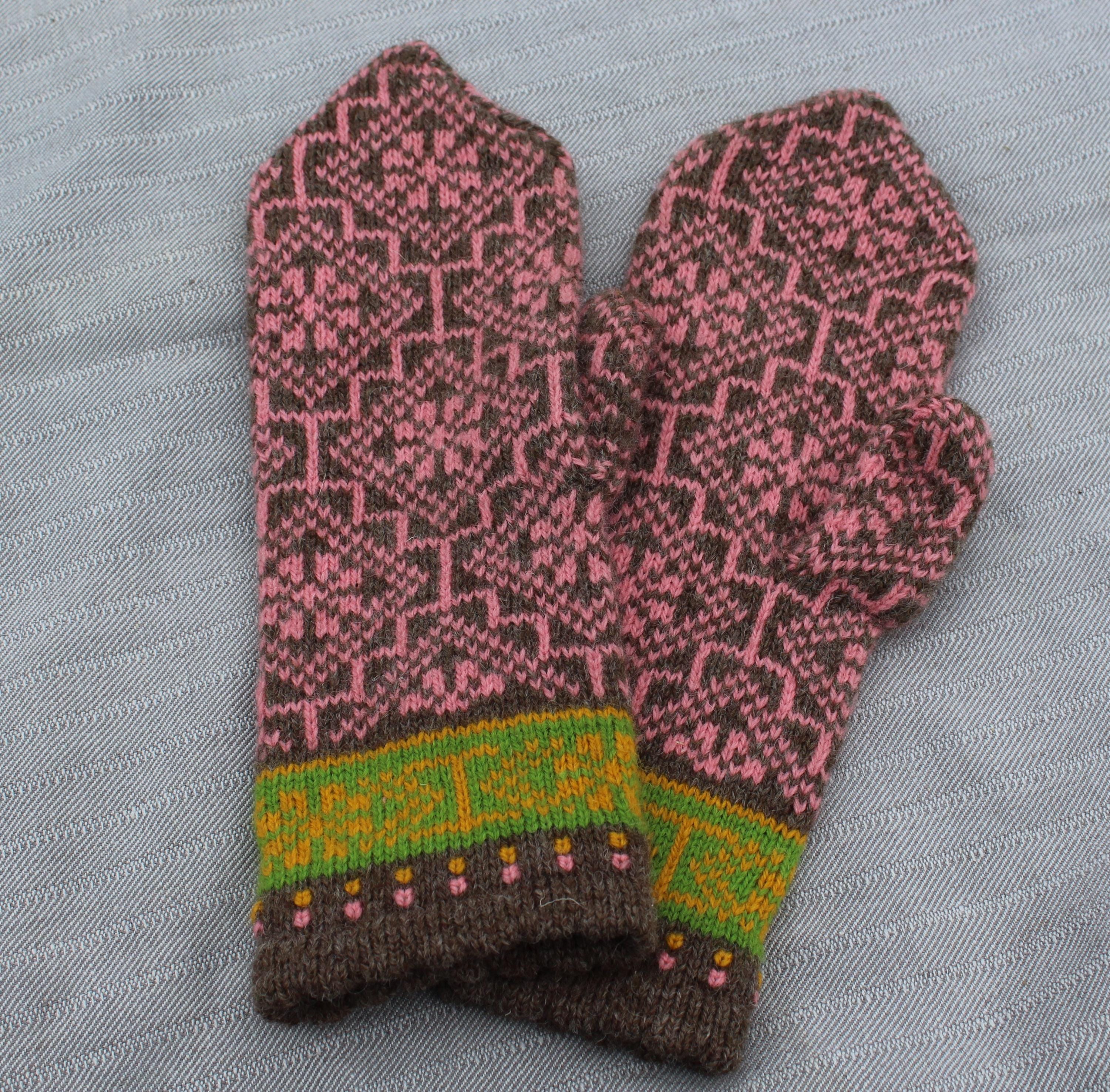 Pair of knitted mittens with a pink and brown pattern on a gray background