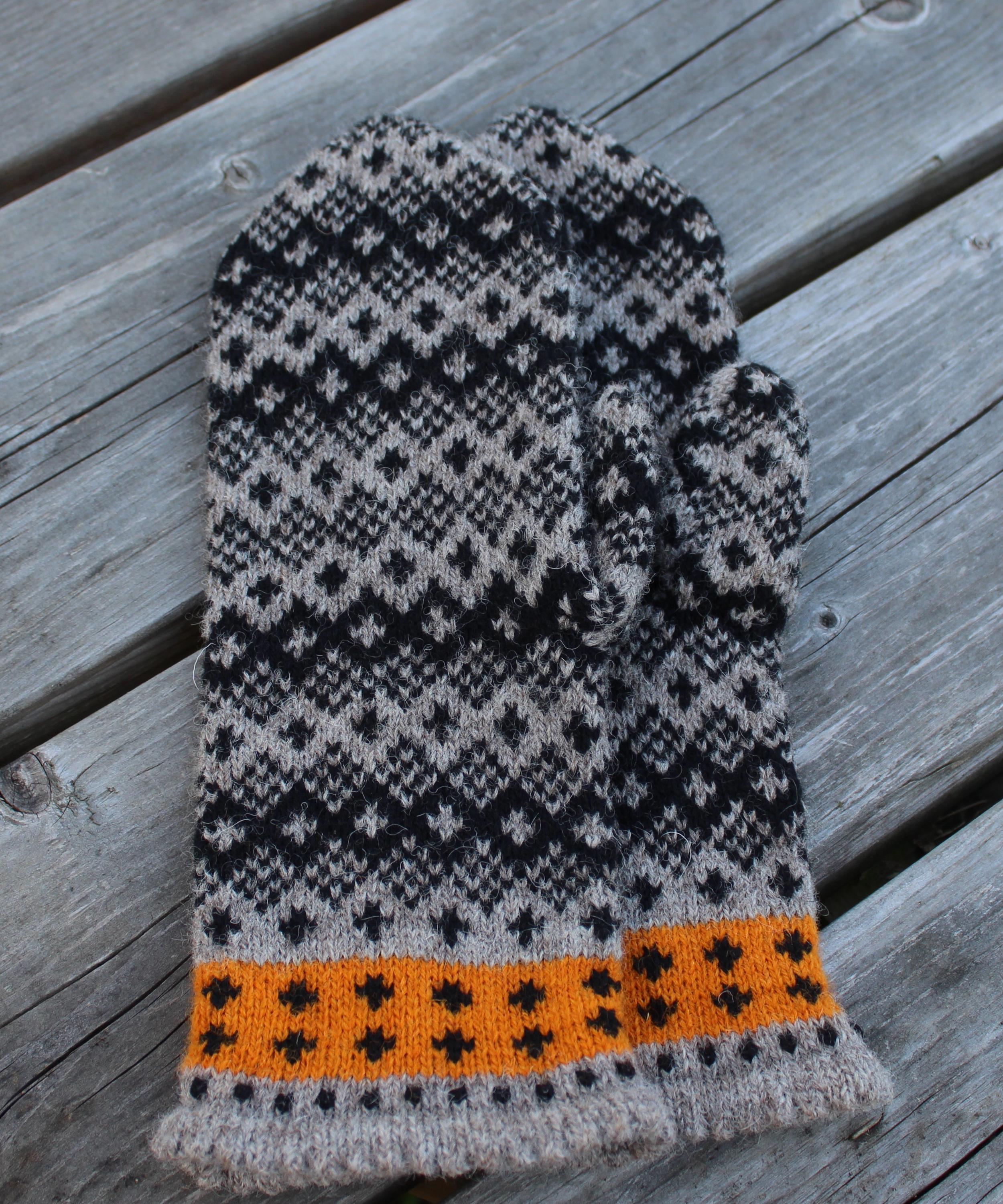 Knitted mitten with a pattern on a wooden surface