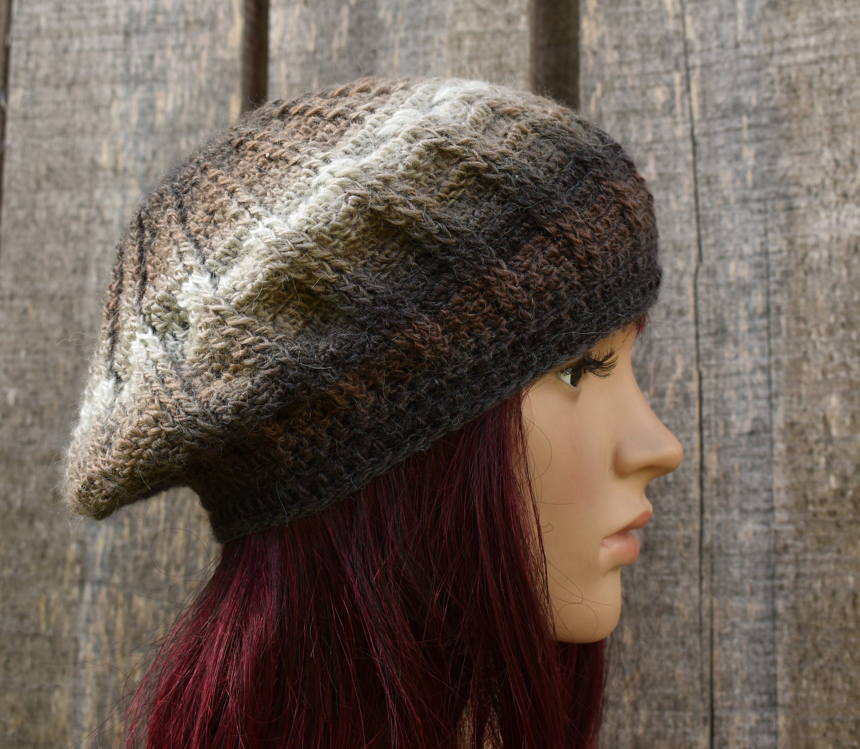 Knitted beret worn by a mannequin against a wooden background