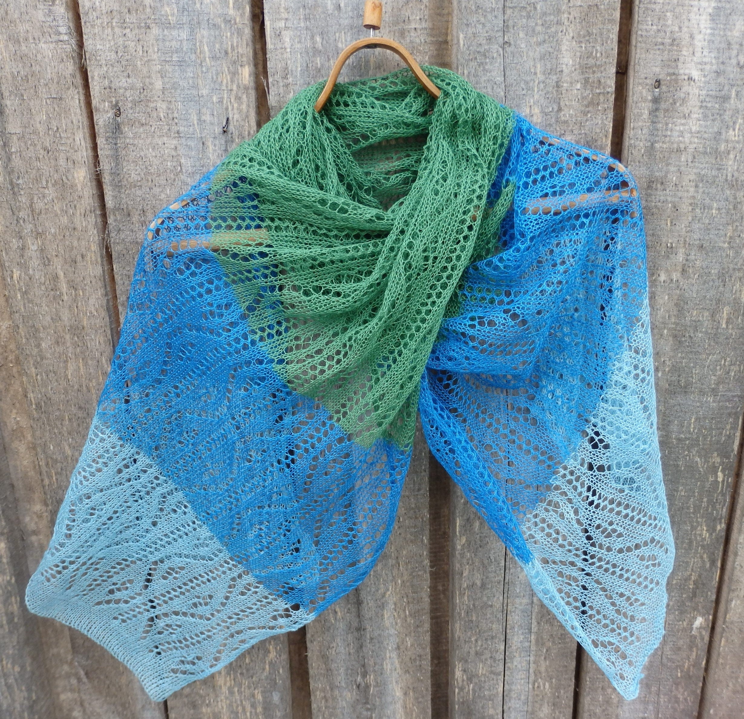 Knitted shawl with blue and green gradient on a wooden background