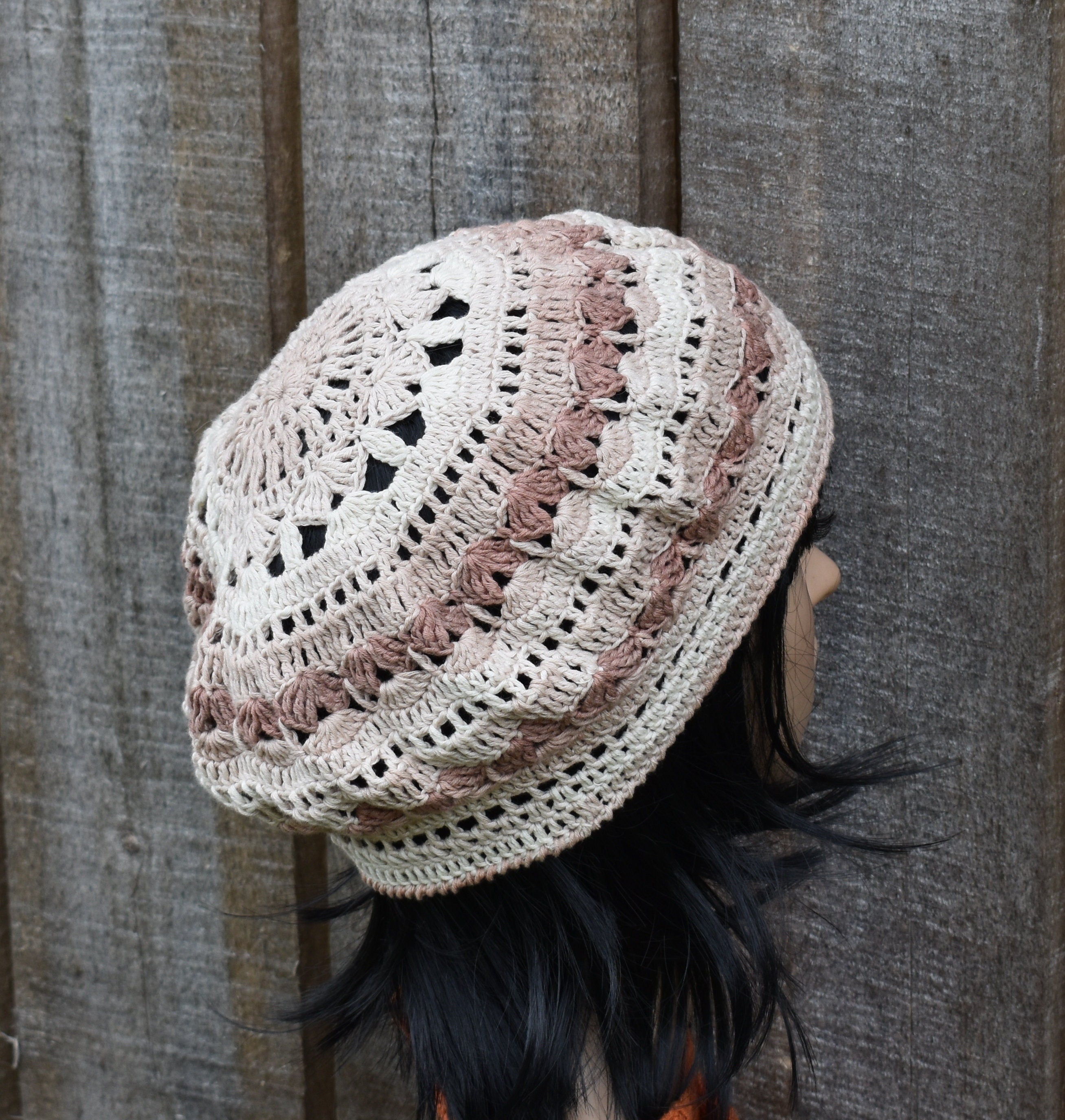 Crocheted beanie with a wavy pattern worn by a person against a wooden background