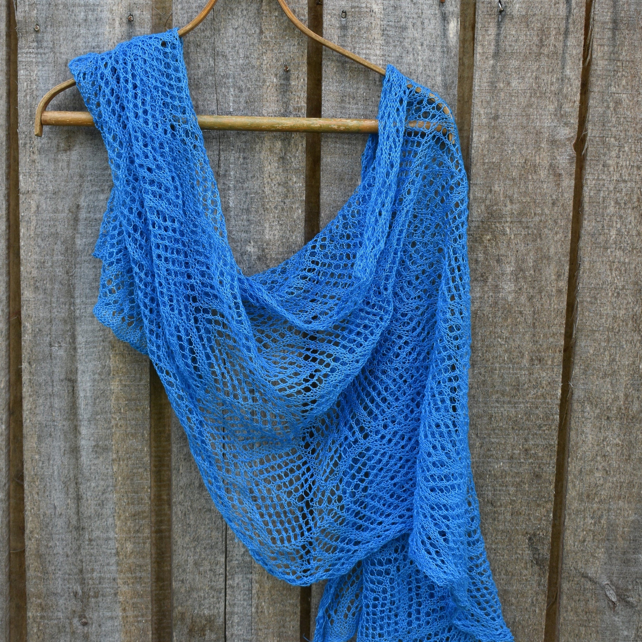 Linen shawl on a wooden hanger against a wooden background