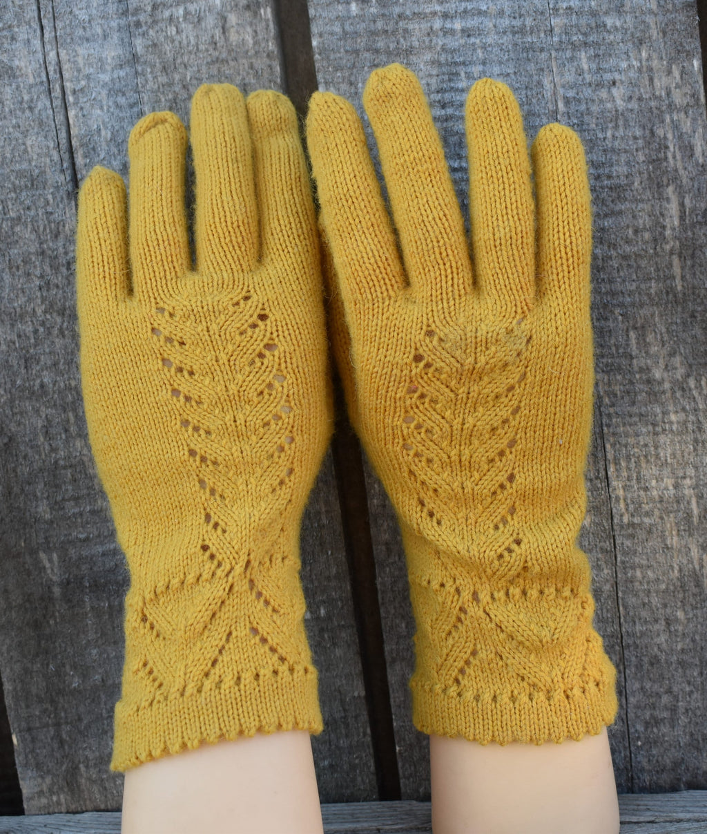 Pair of mustard yellow knitted gloves on a wooden surface
