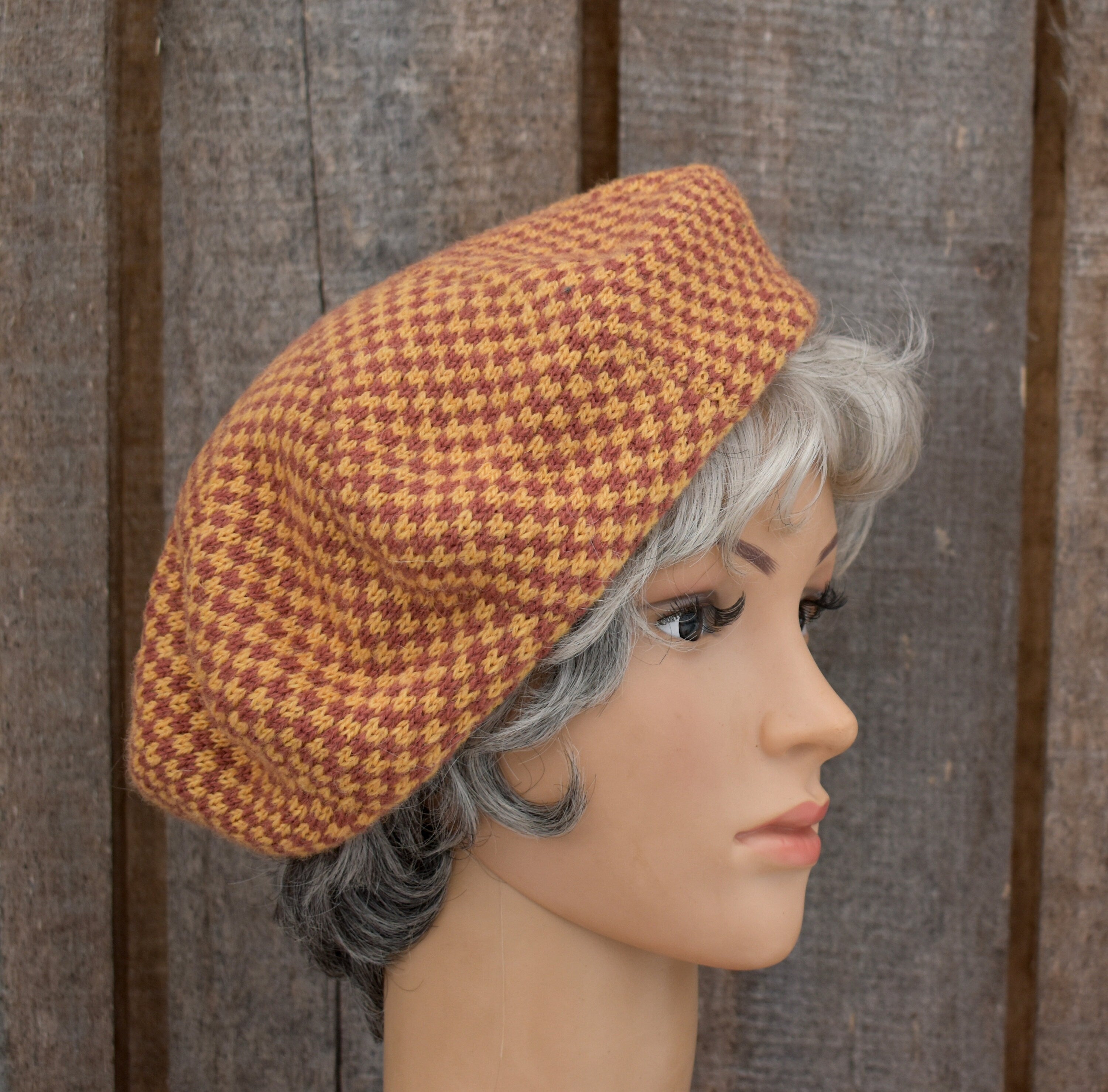 Mannequin head wearing a brown houndstooth patterned hat against a wooden background