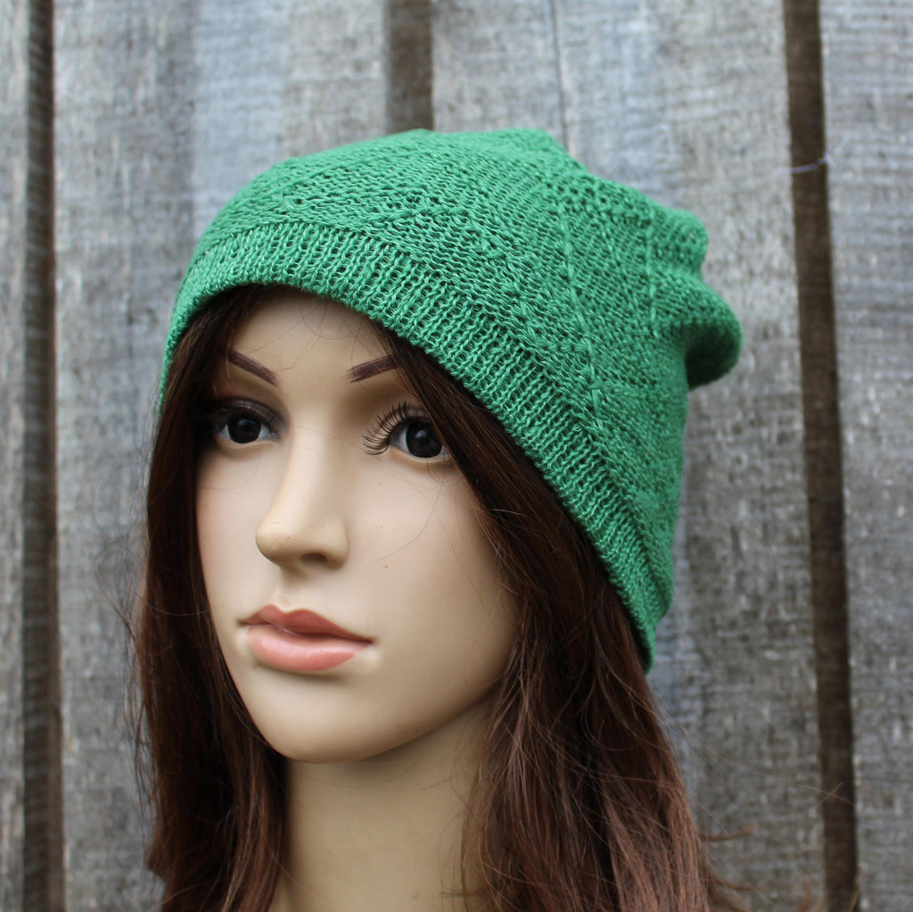 Green knitted beanie on a mannequin head against a wooden background