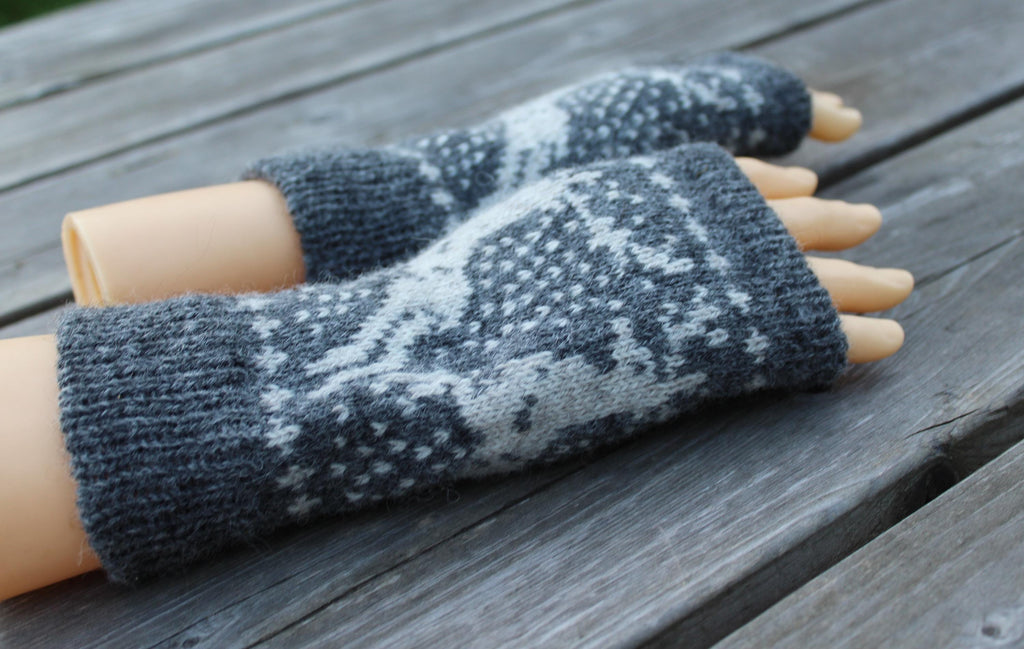 Pair of gray and white patterned fingerless gloves on a wooden surface