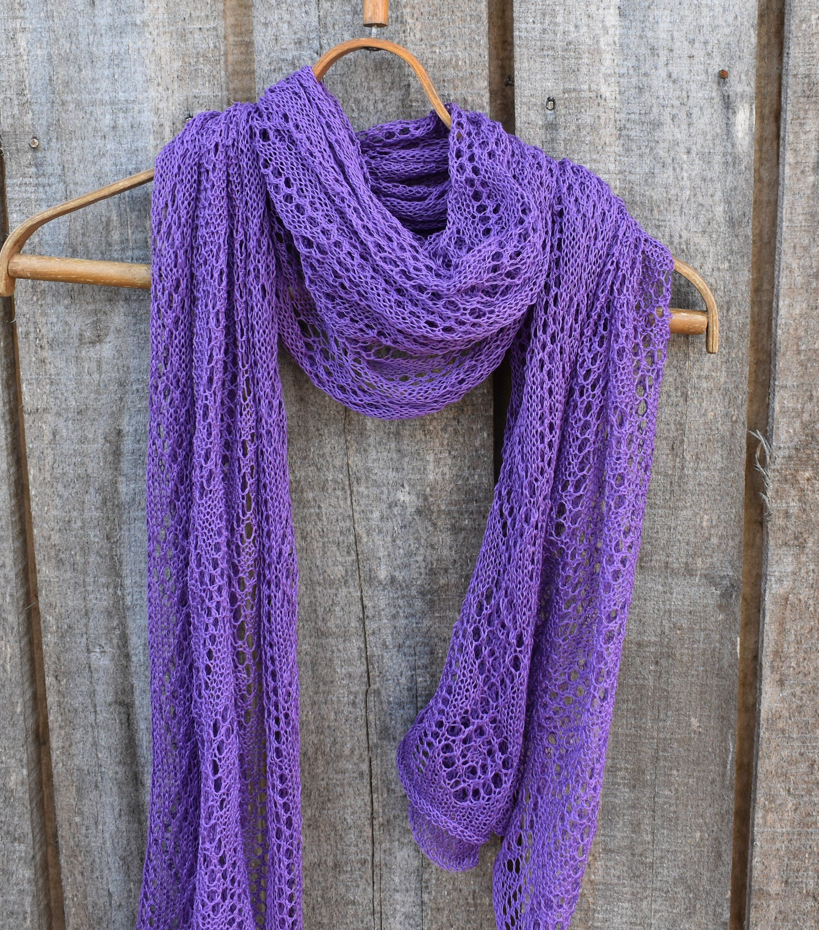 Purple lace scarf on a wooden hanger against a rustic wooden background