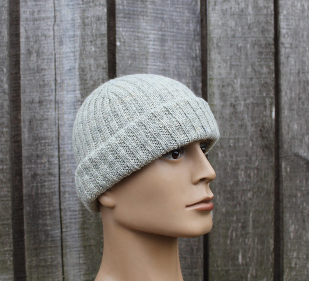 Mannequin head wearing a gray knit beanie against a wooden background