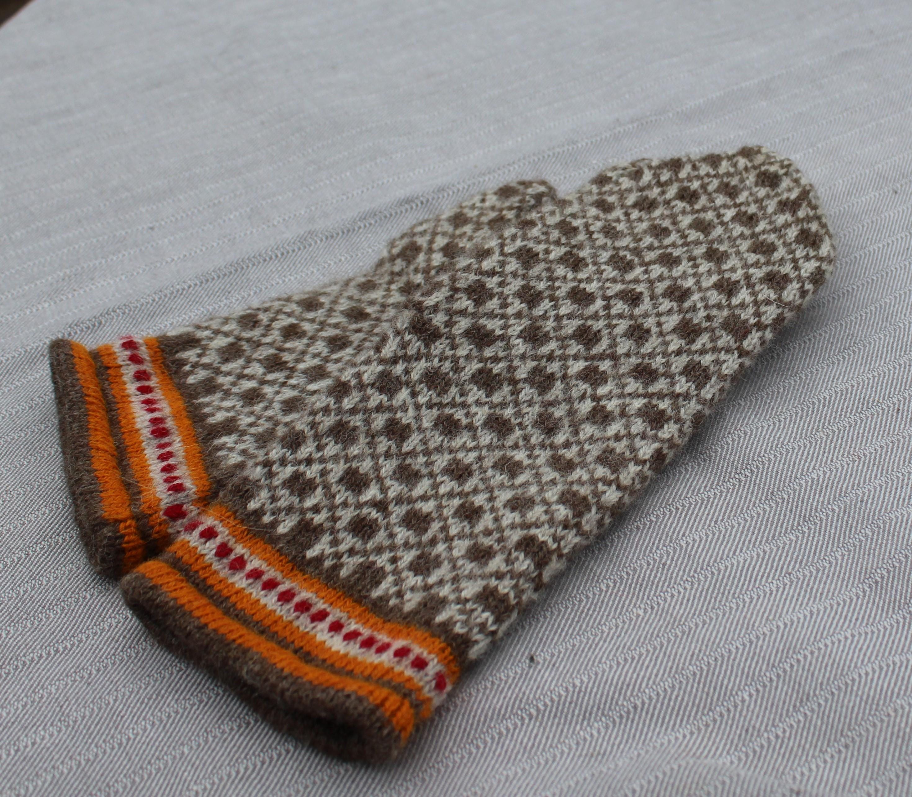 Knitted mitten with a pattern on a gray background