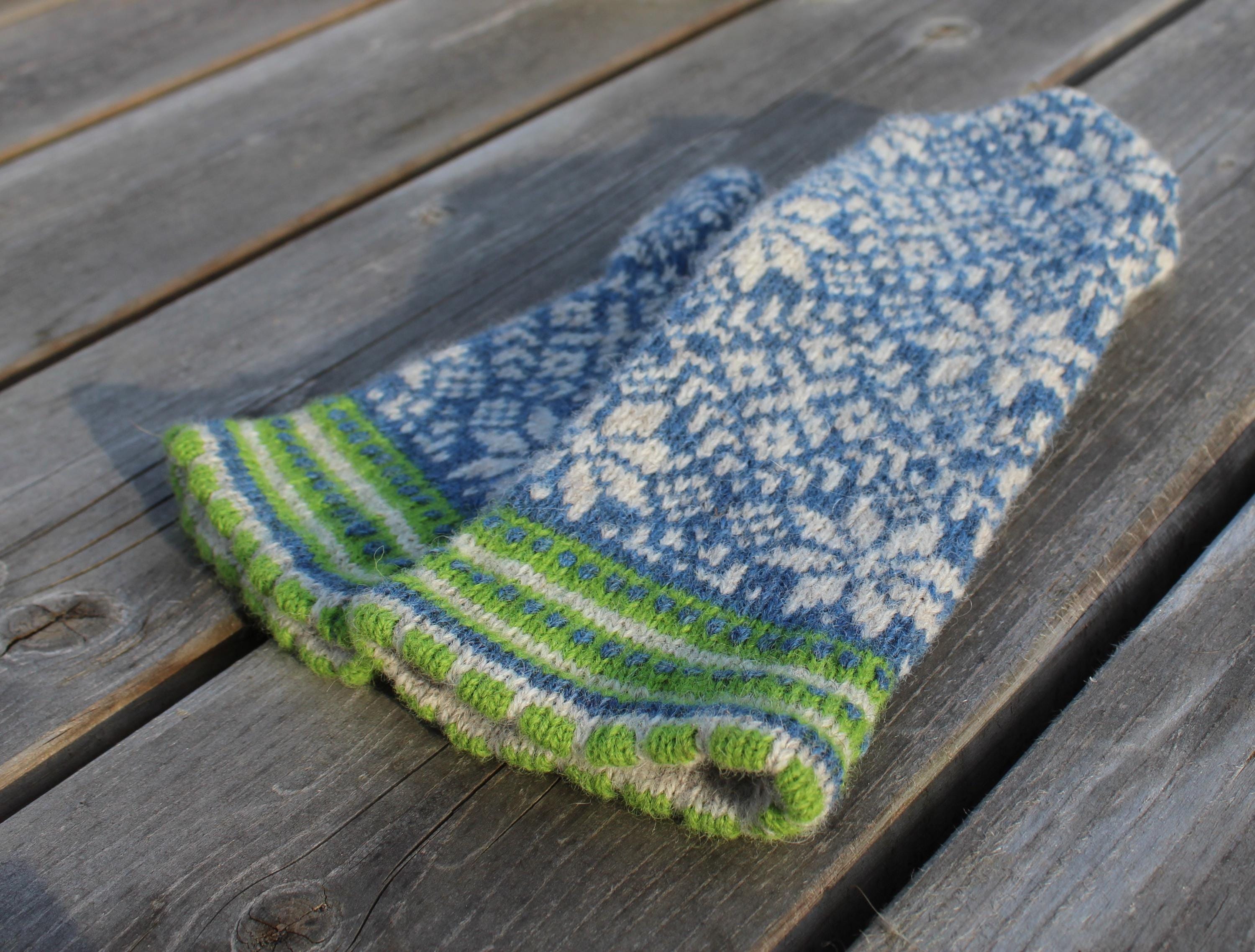 Knitted blue and green sock on a wooden surface