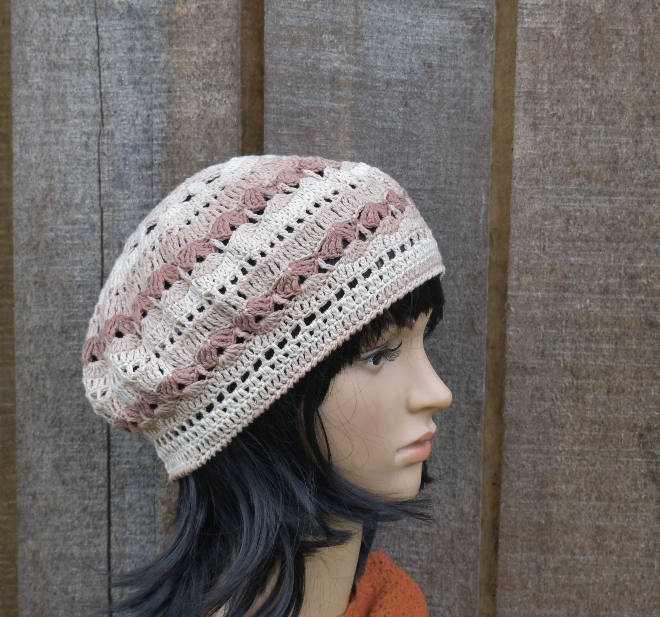 Mannequin head wearing a crocheted beanie with a wooden background