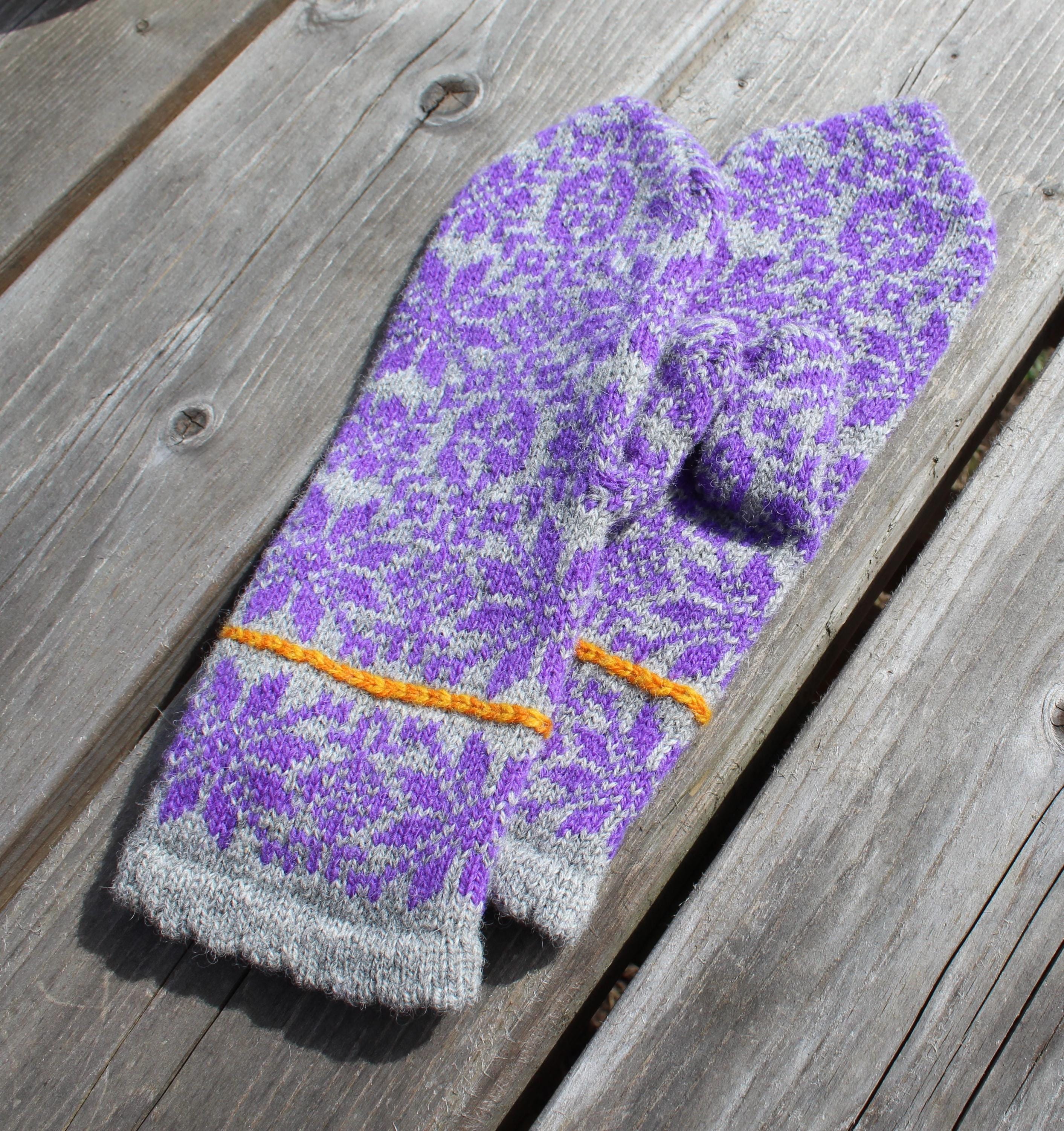 Pair of purple and gray knitted mittens on a wooden surface