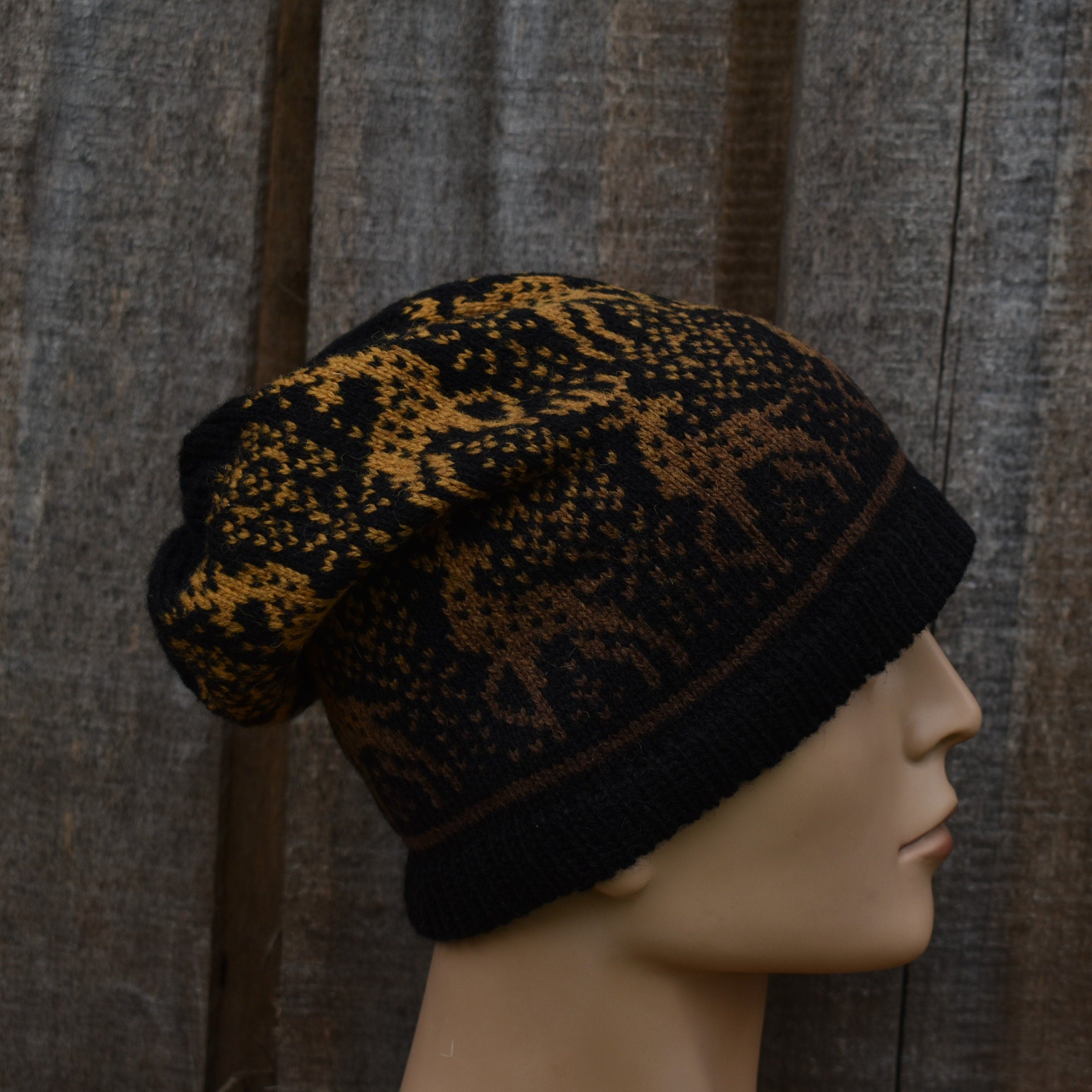 Black and gold patterned beanie on a mannequin head against a wooden background