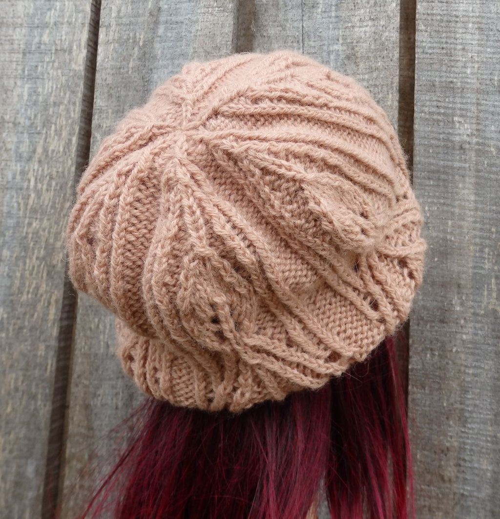 Knitted beige beanie on a person with red hair against a wooden background
