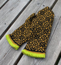 Pair of black and yellow patterned mittens on a wooden surface