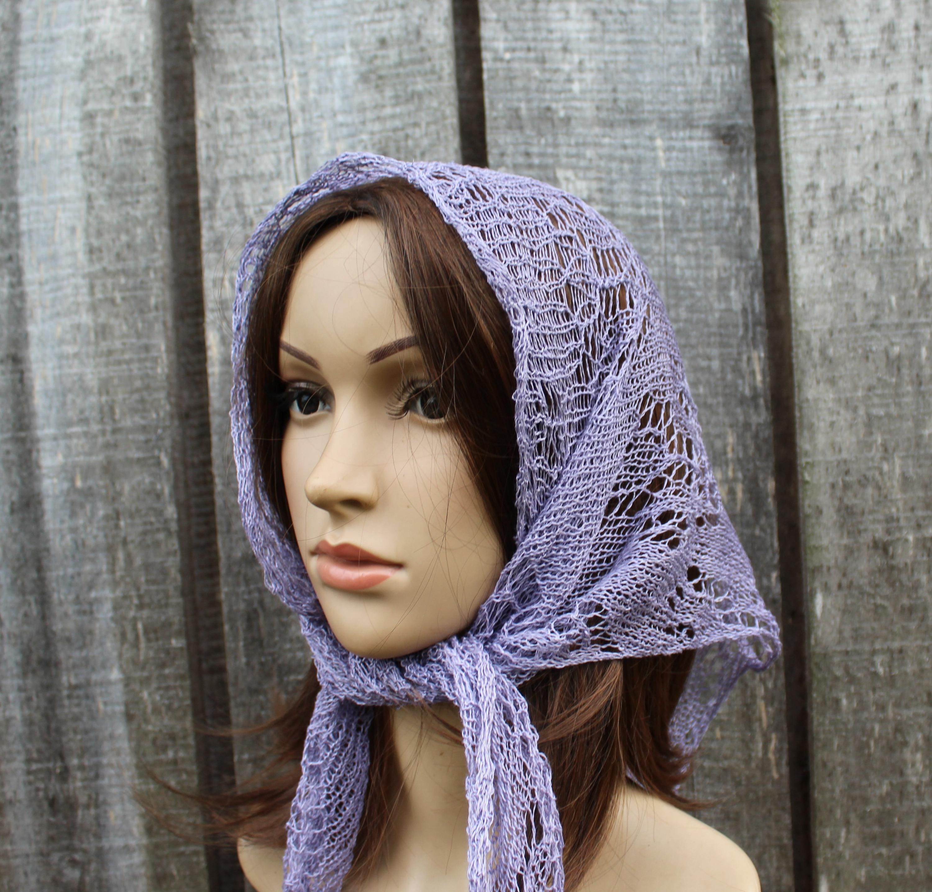 Mannequin head wearing a purple lace headscarf against a wooden background