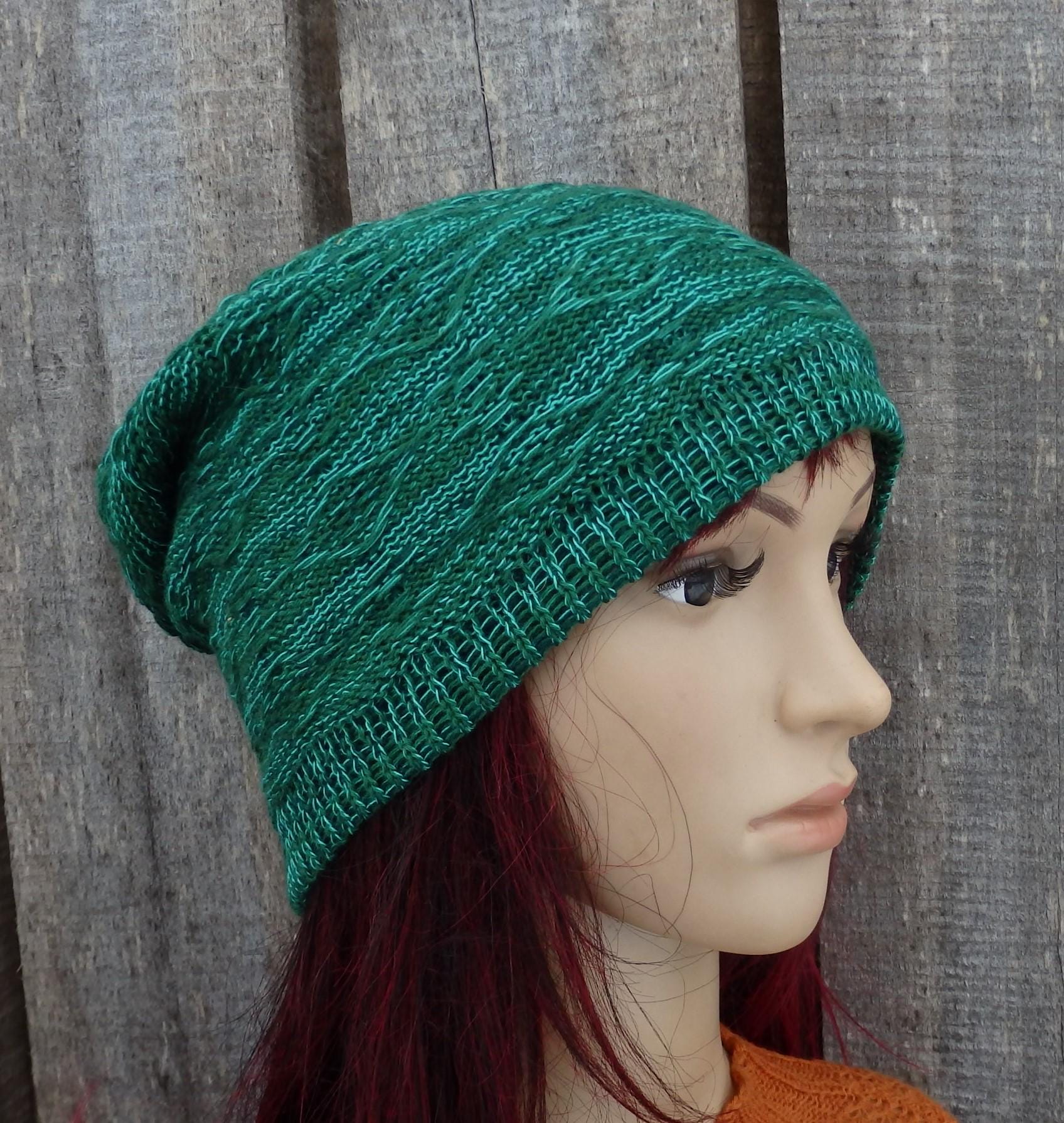 Green knitted beanie on a mannequin head against a wooden background