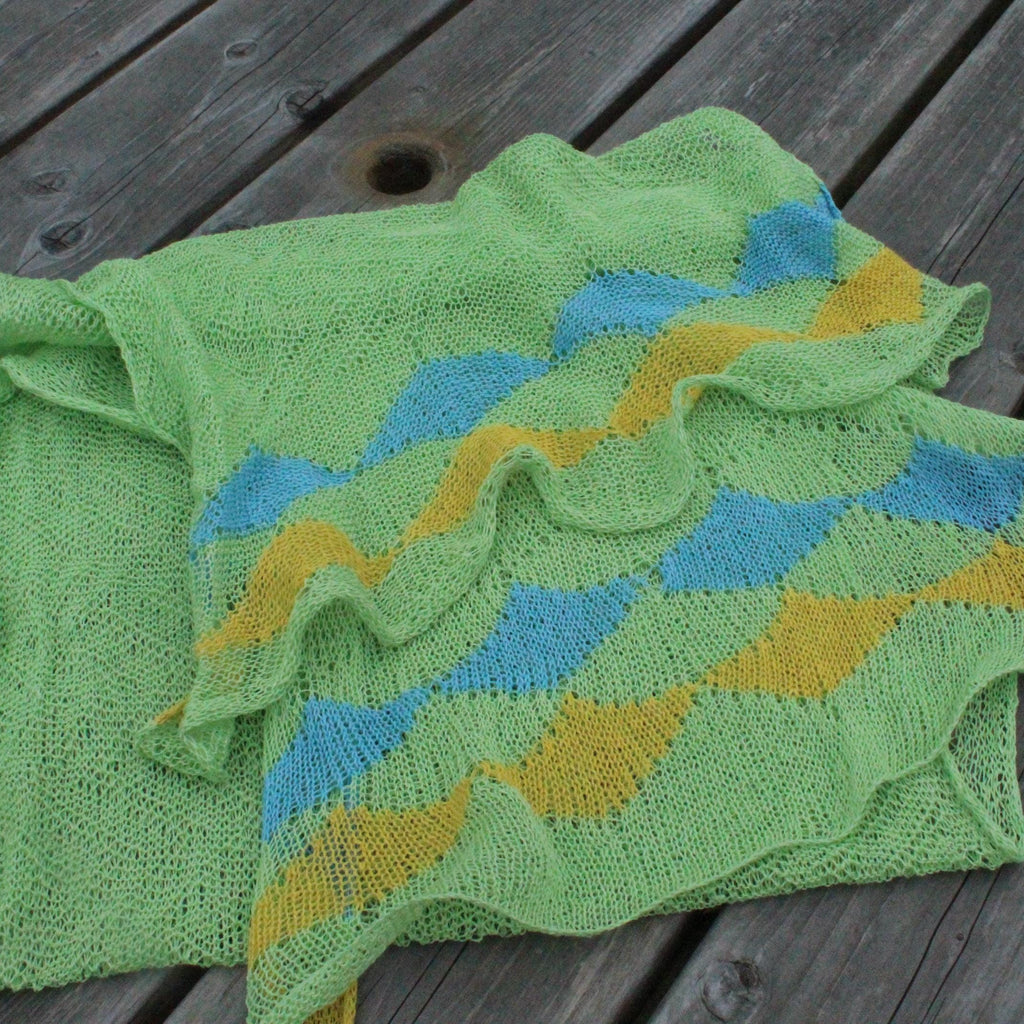 Green, blue, and yellow knitted blanket on a wooden surface