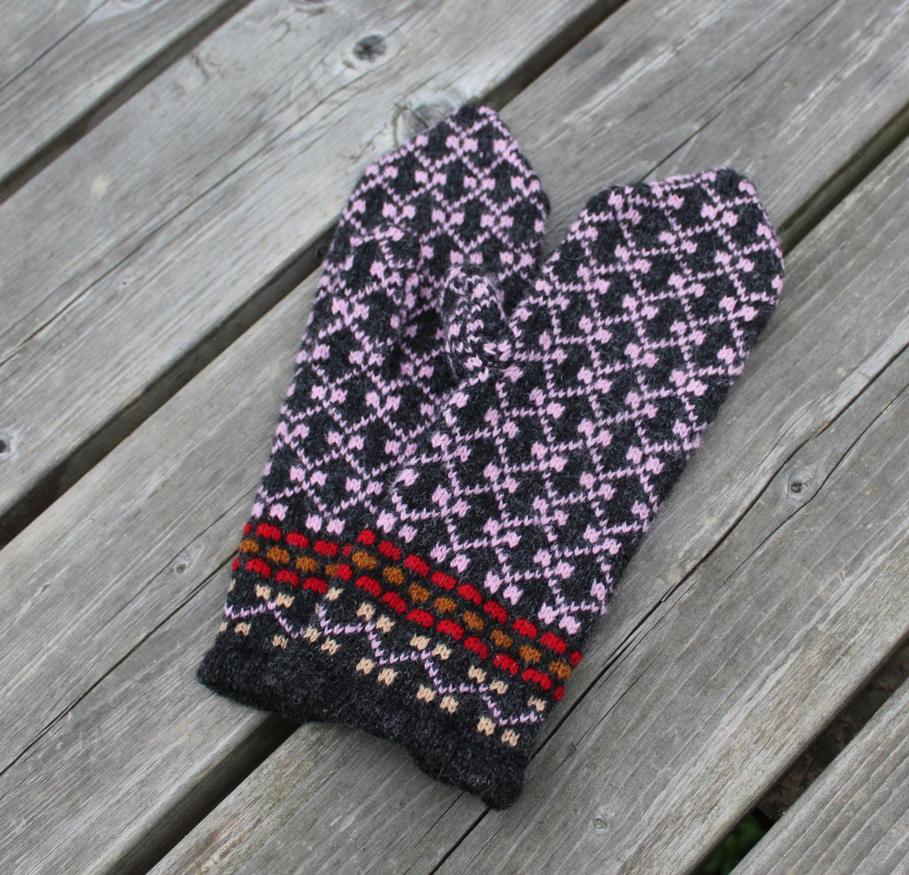 Pair of knitted mittens with a geometric pattern on a wooden surface